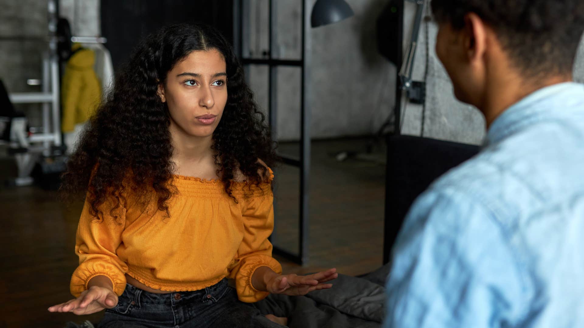 woman in orange shirt expressing boundaries and opinions as man in blue shirt in respects her