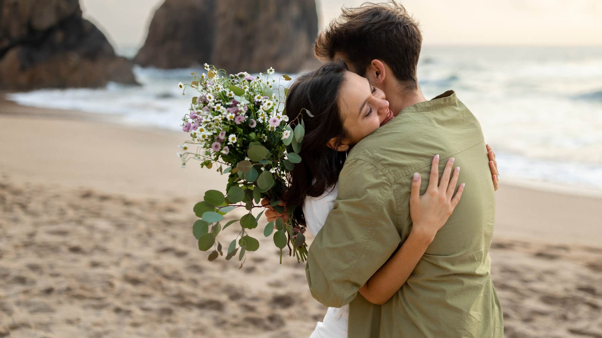 man gifting woman flowers as he surprises her with small gestures and she smiles happily
