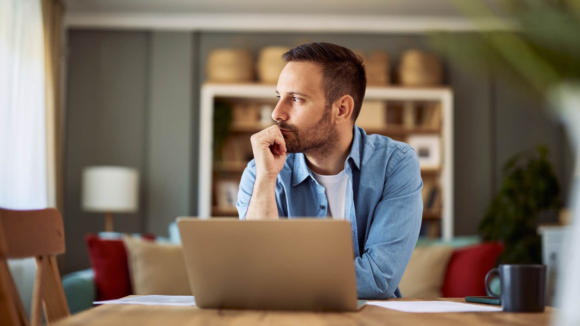 man contemplating in front of laptop
