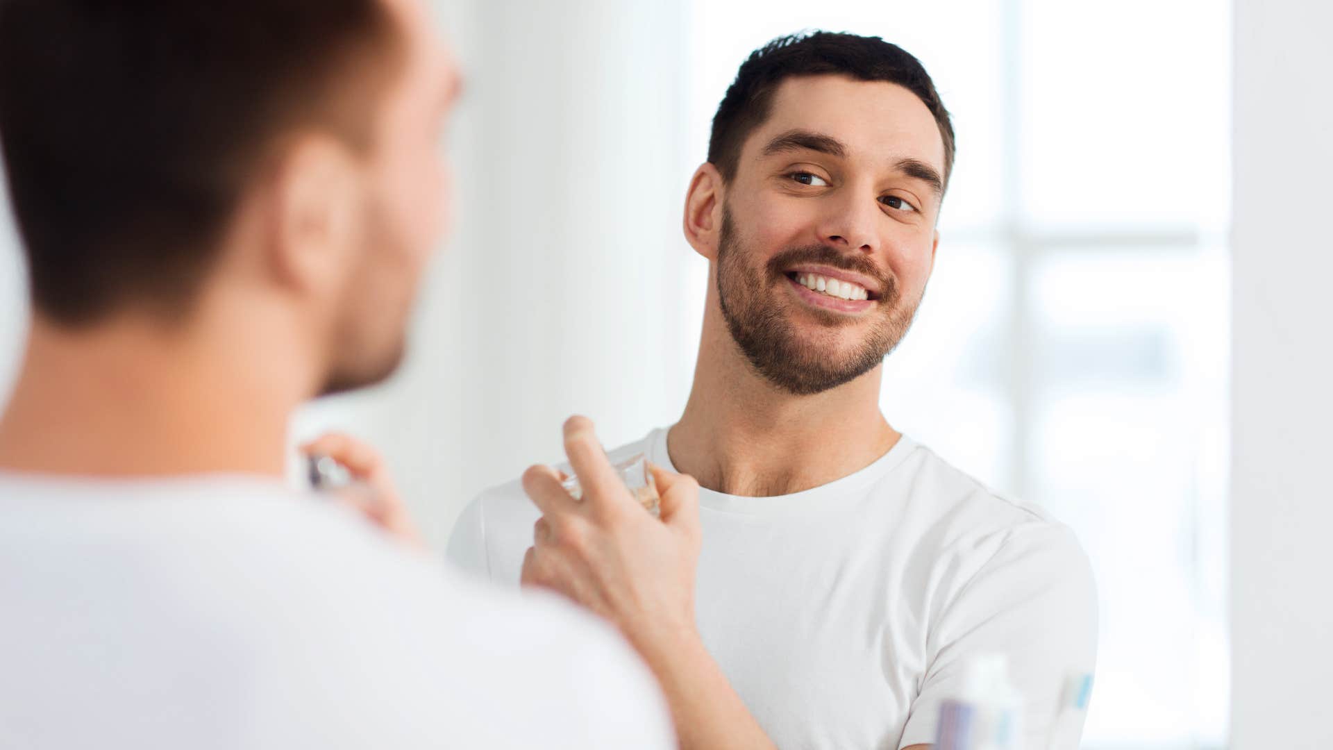 man smiling using perfume instead of bathing