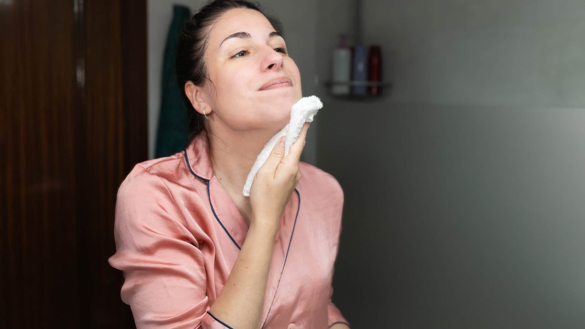woman looking in the mirror reusing an old towel on her face