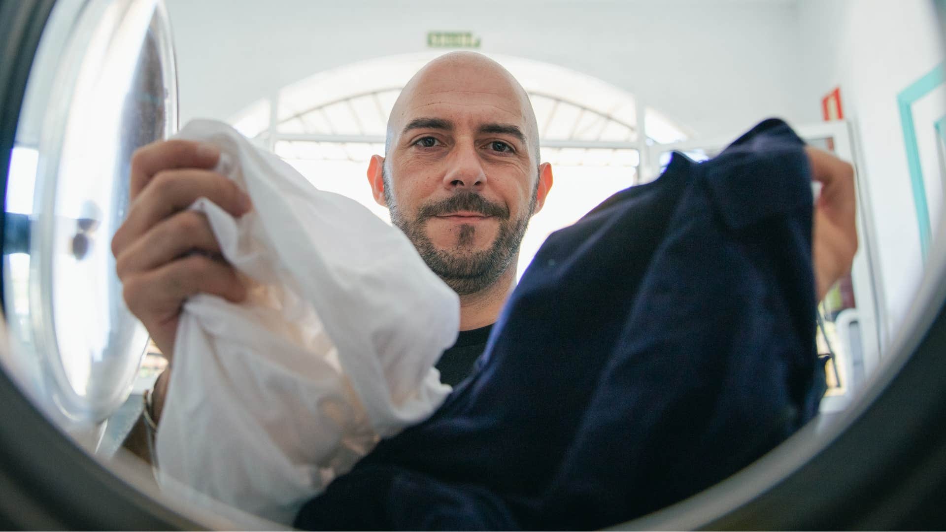 man looking in his dryer and wearing damp clothes