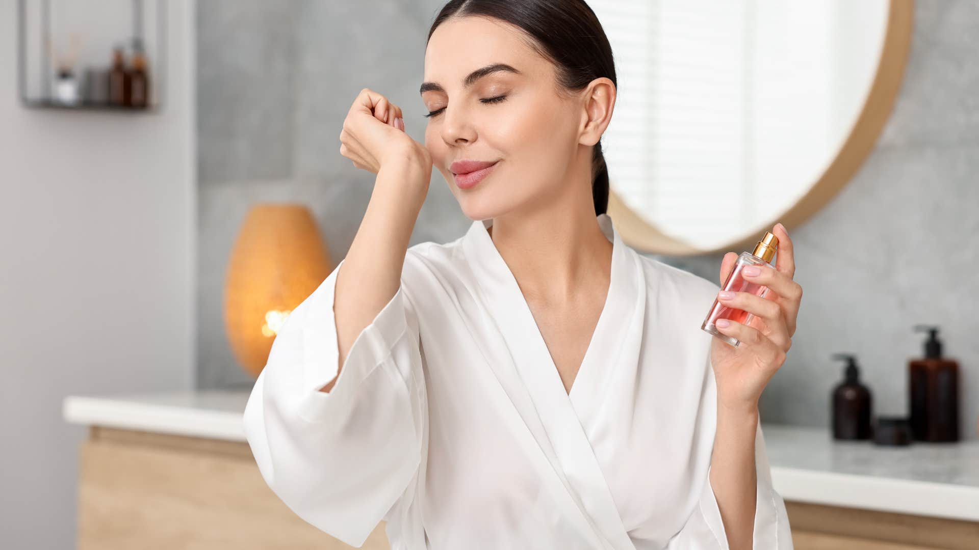 woman smelling herself after spraying perfume
