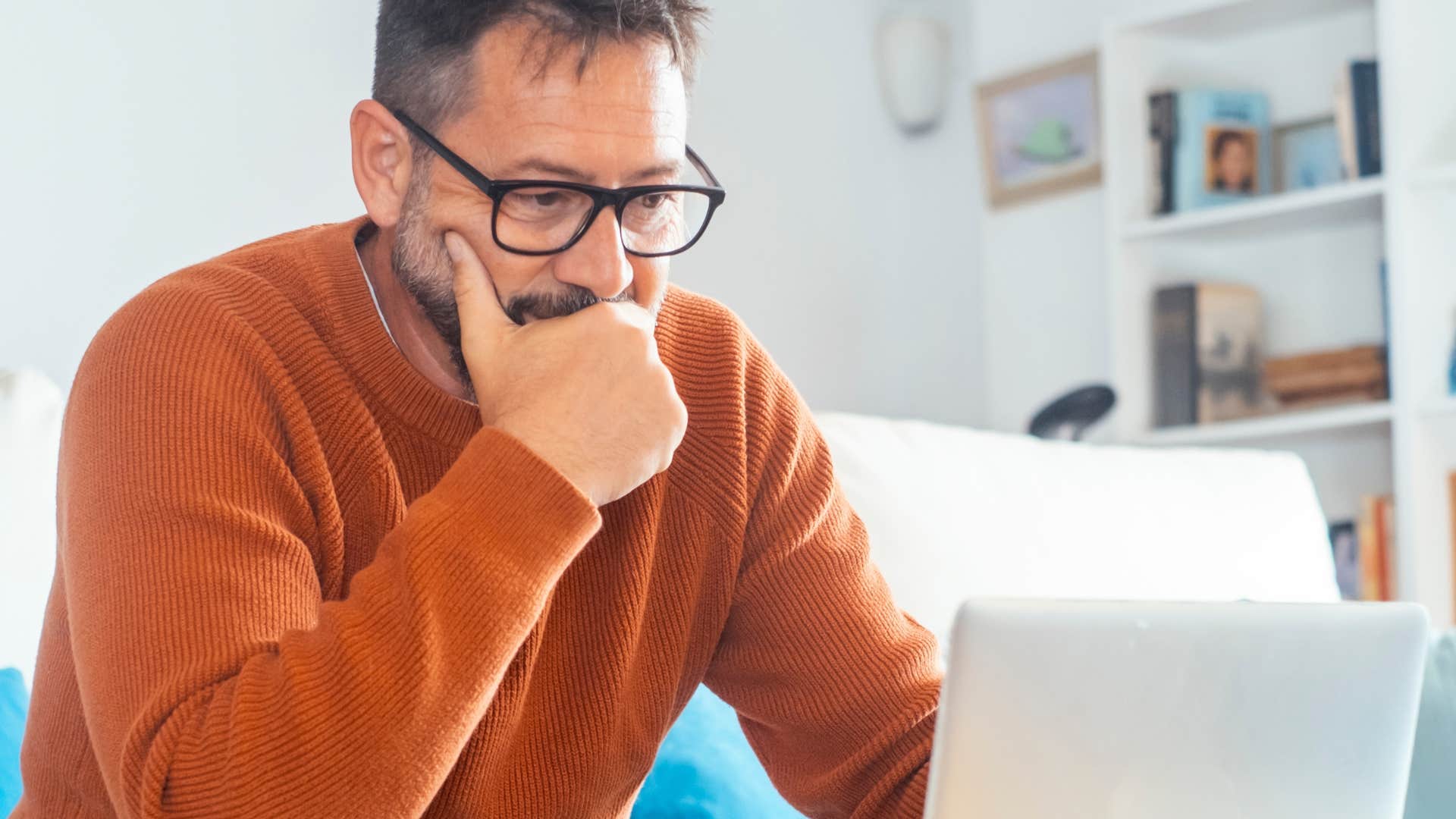 man thinking about movie plot twists while looking at laptop