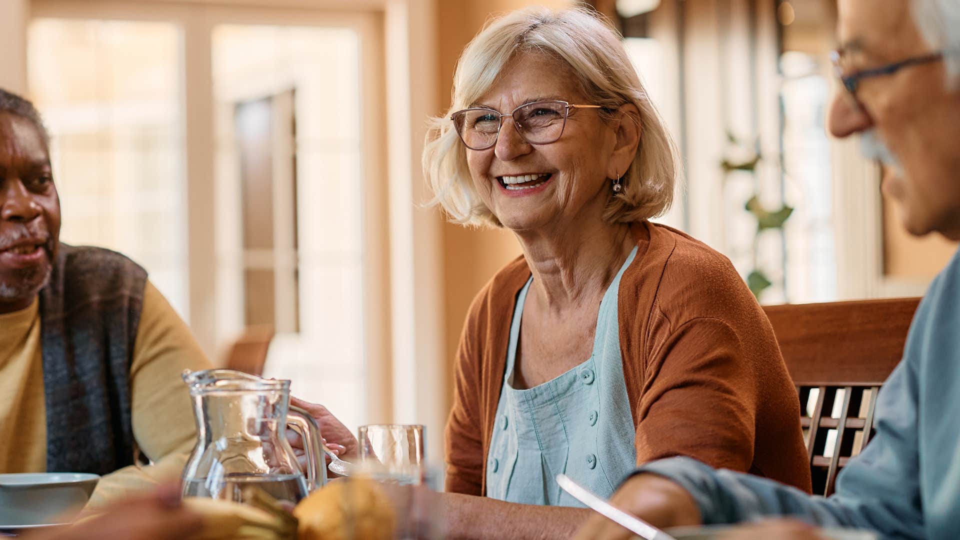 woman smiling at dinner with friends holding cloth napkin