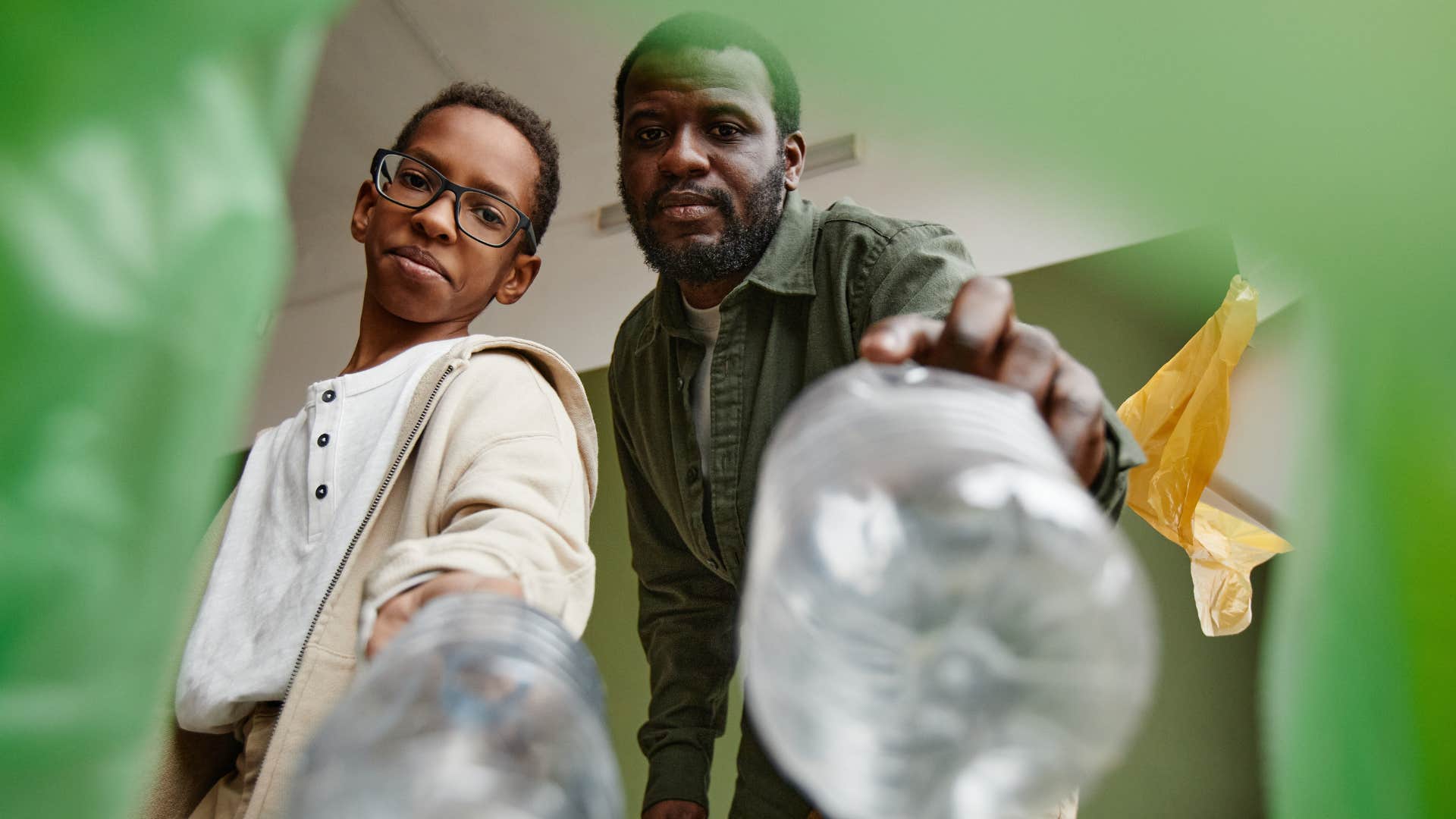 man and his son putting bottles into recycling bins