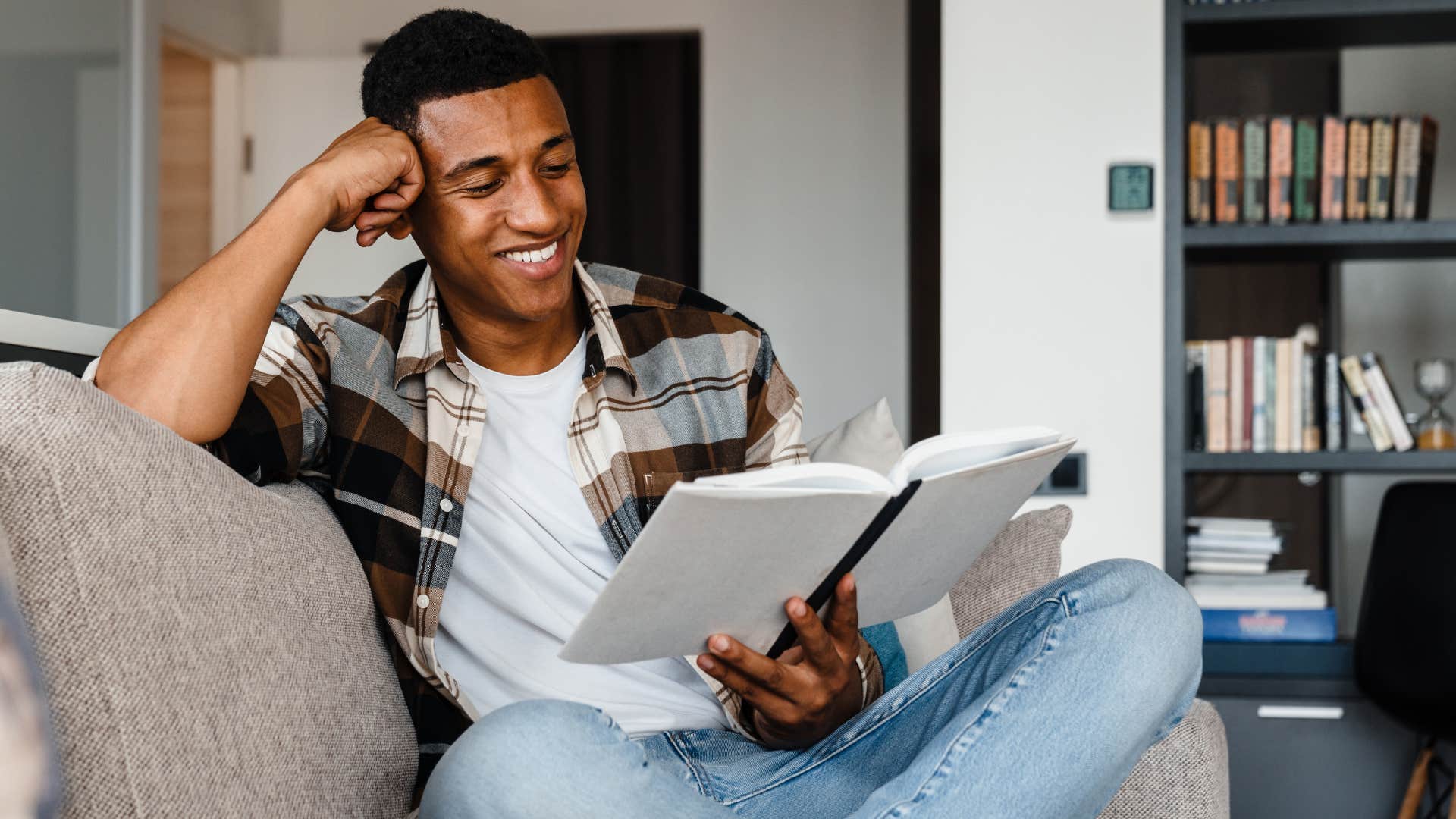 Man smiling and reading books at home.