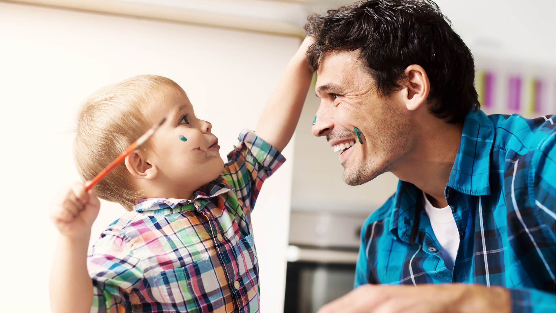 Man smiling and playing with creative supplies with his son.