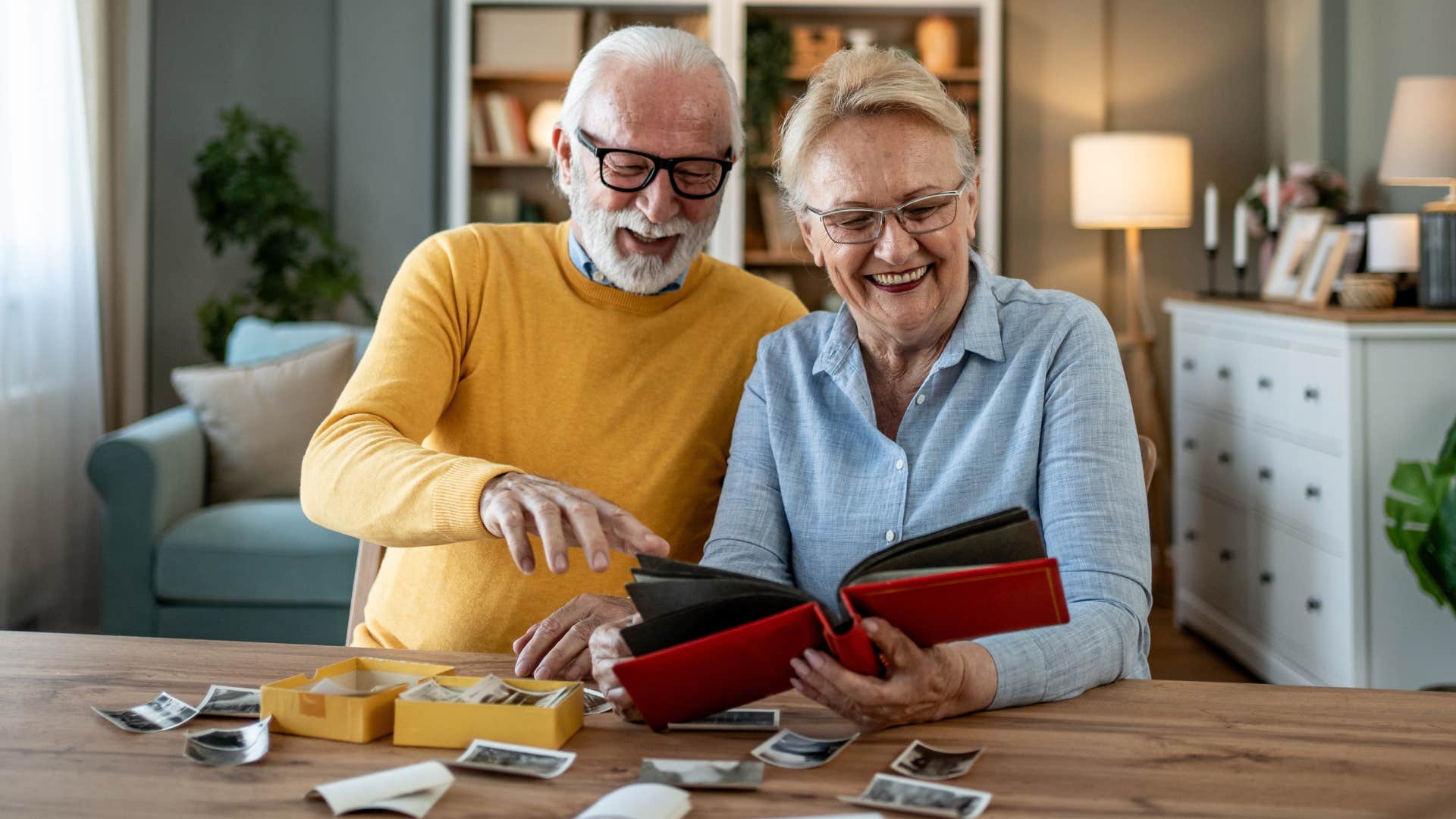 Couple smiling and looking at meaningful artwork and photos at home.