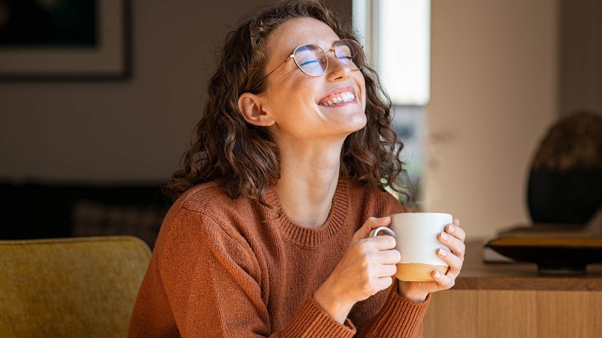 Woman smiling and drinking tea at home.