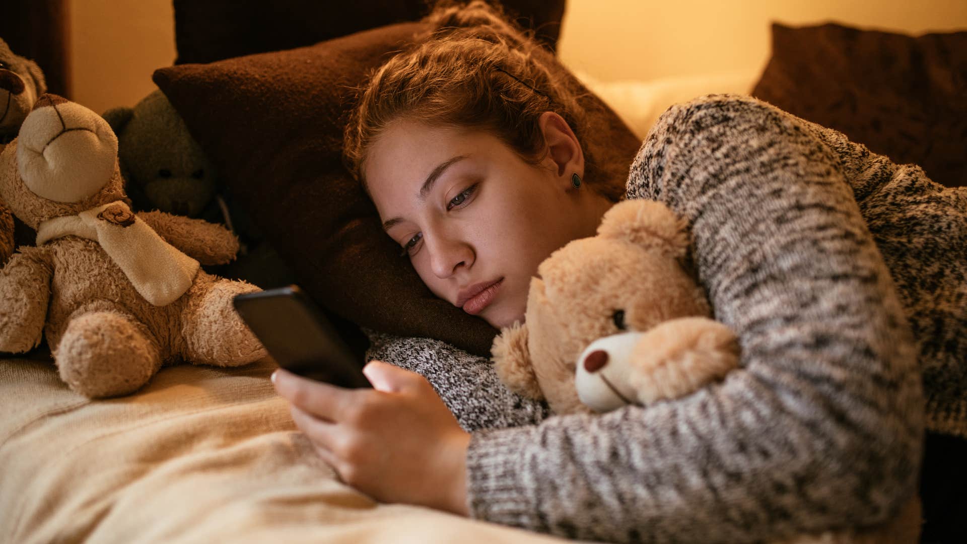 woman holding childhood toys in her bed