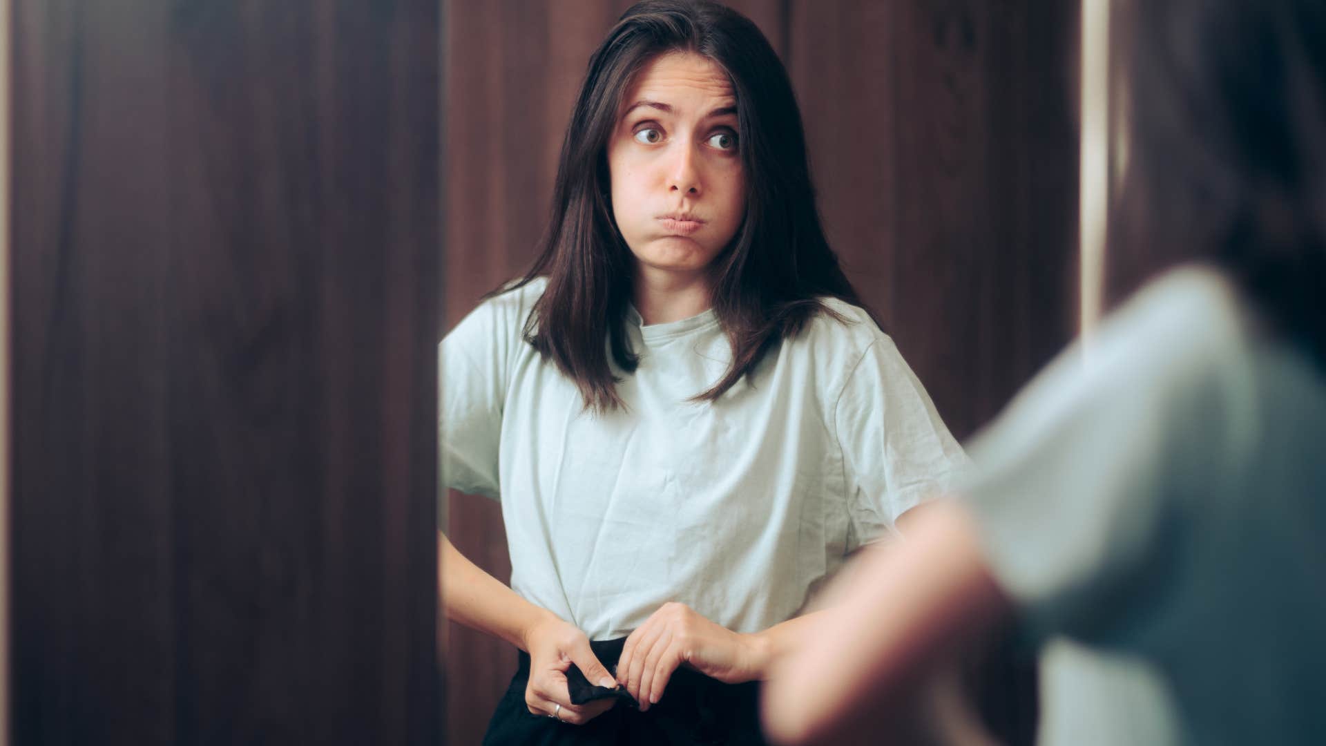 woman getting dressed in clothes that don't fit