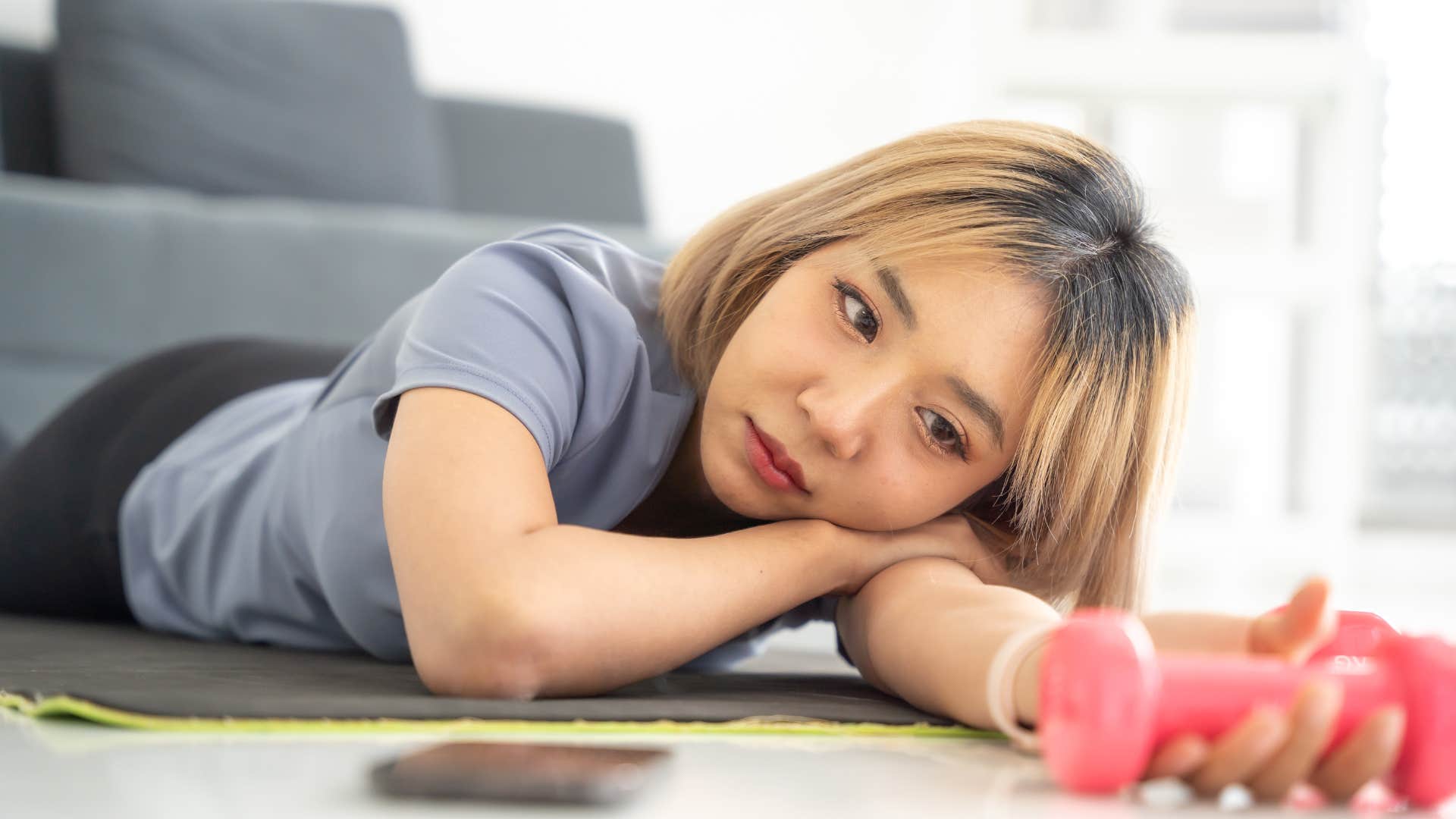 sad woman looking at unused exercise equipment
