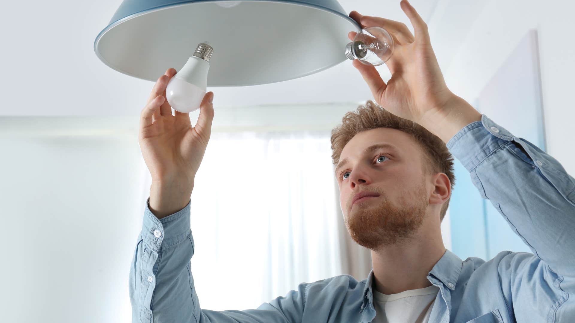 man replacing burnt-out light bulbs at home