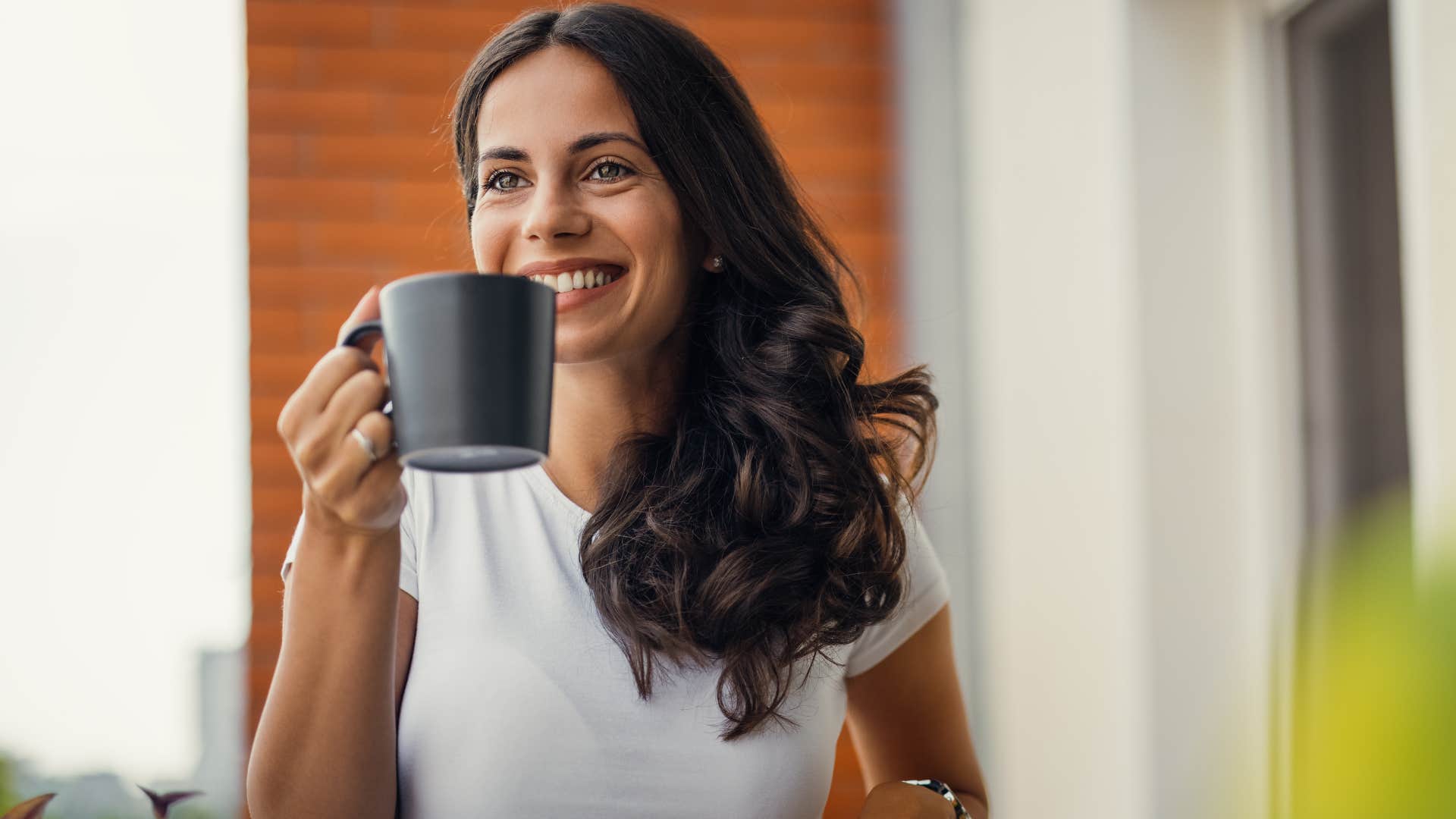 woman smiling and drinking coffee from the pod