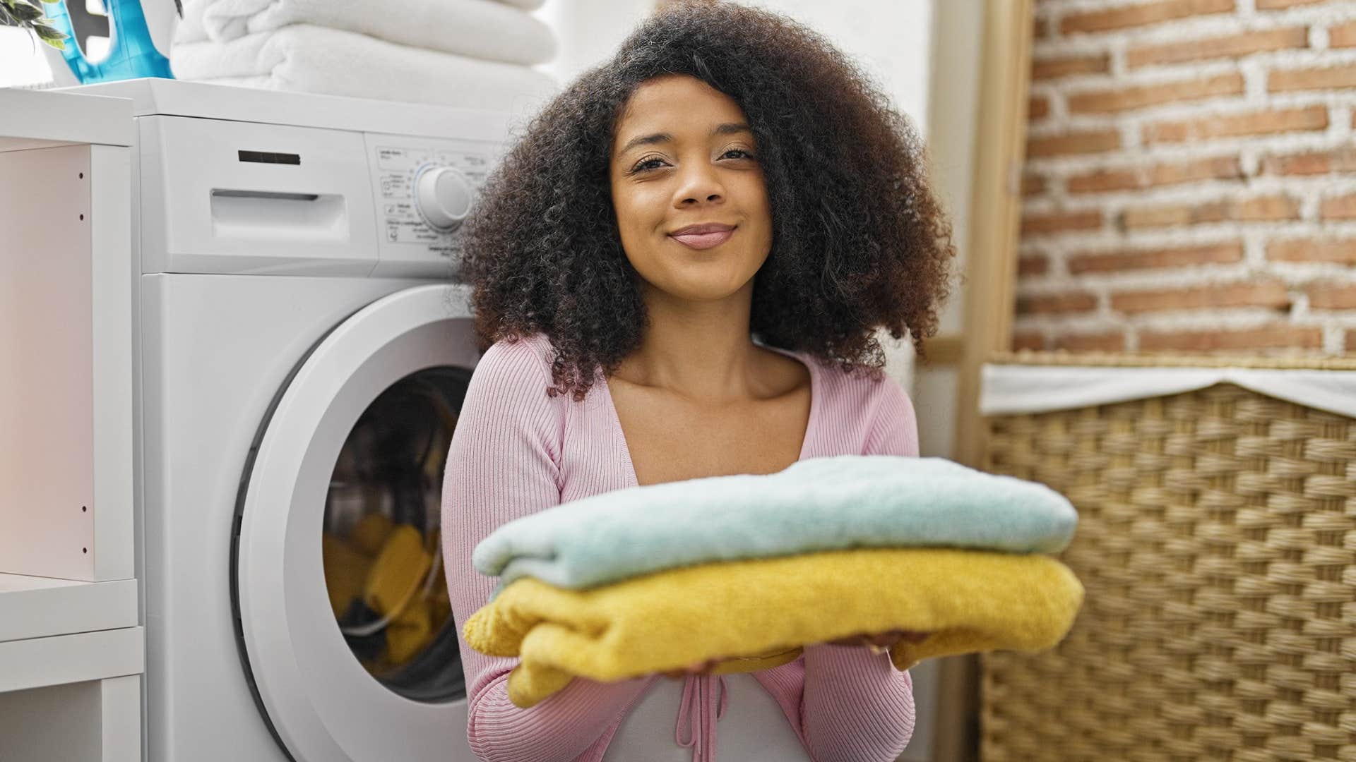 woman smiling and holding towels in laundry room