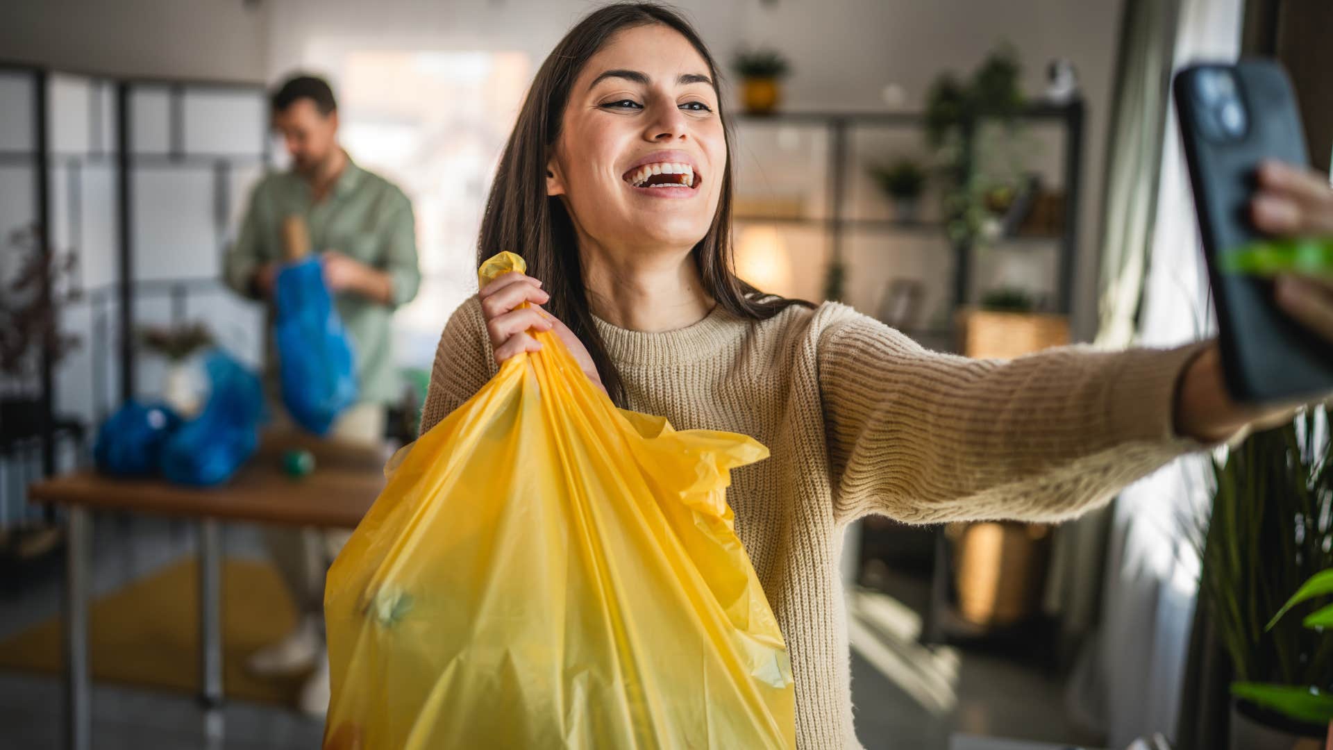 woman smiling and holding up single-use plastic bag