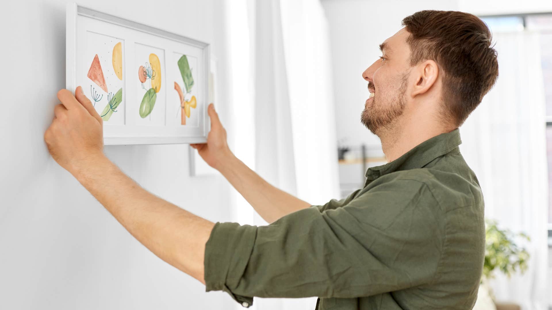 man smiling and hanging up trendy framed art