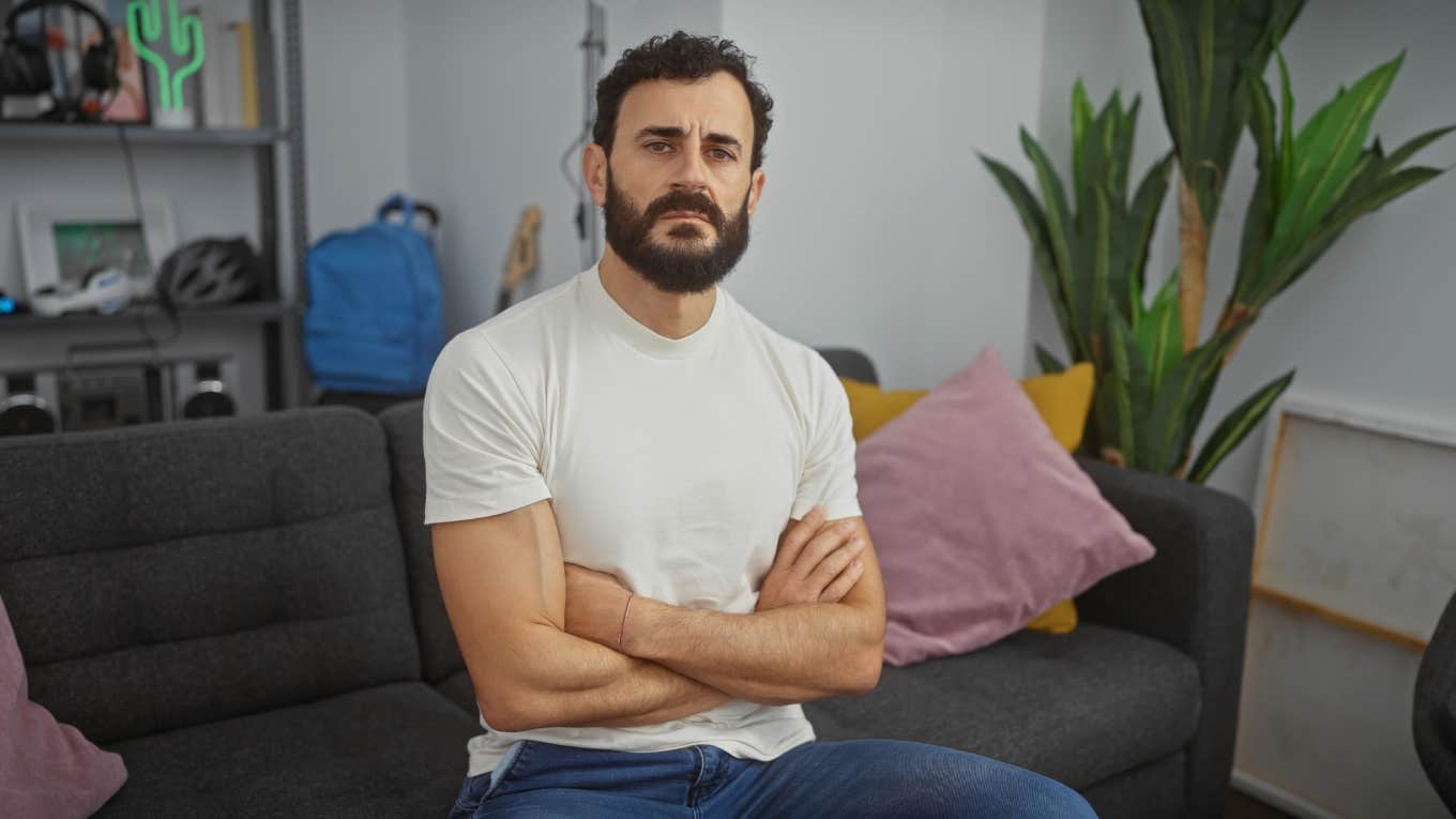 Man Says Having A Favorite Color Is Childish serious man sitting on couch with arms crossed