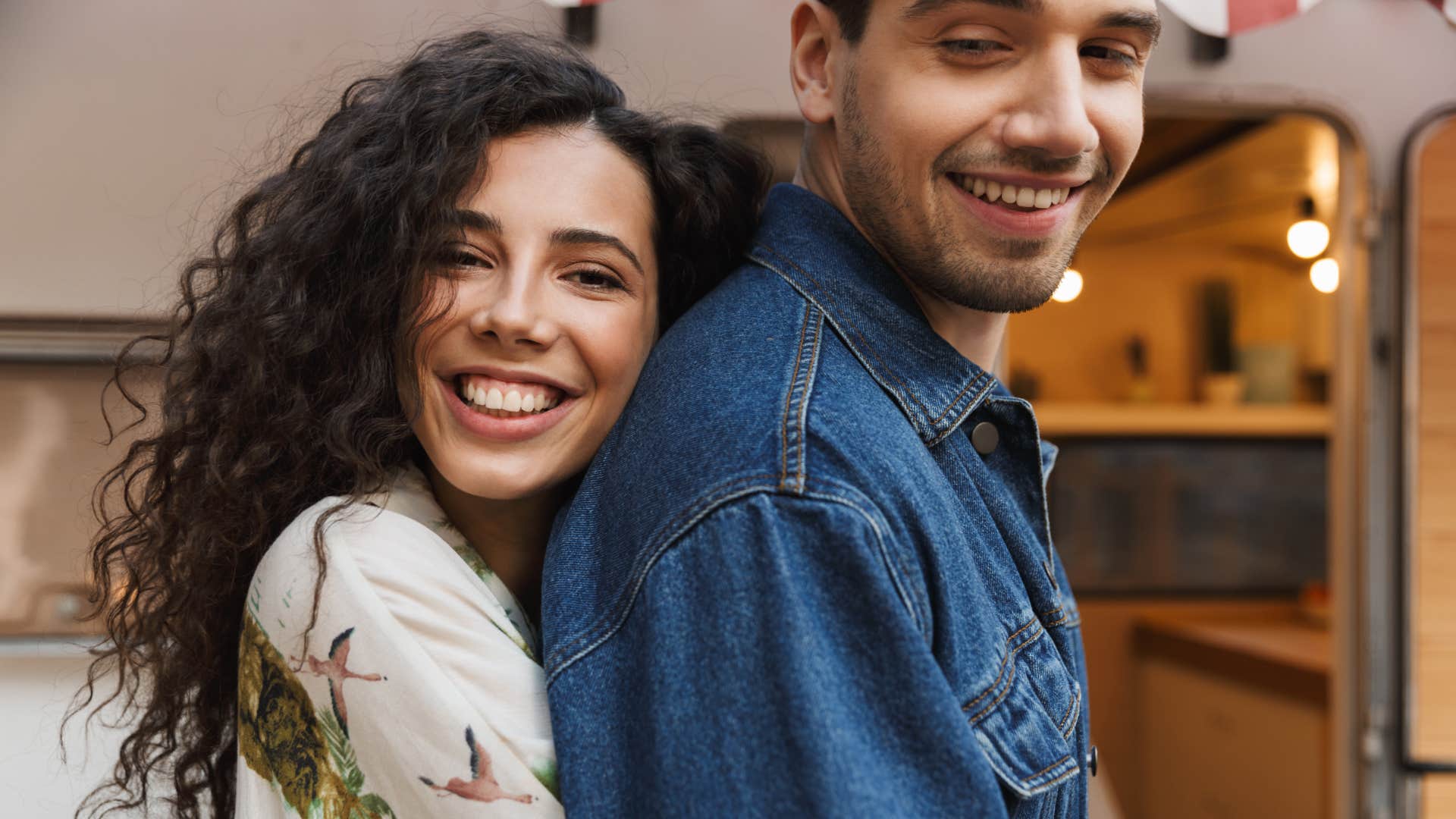 woman hugging man from behind enjoying spending time together