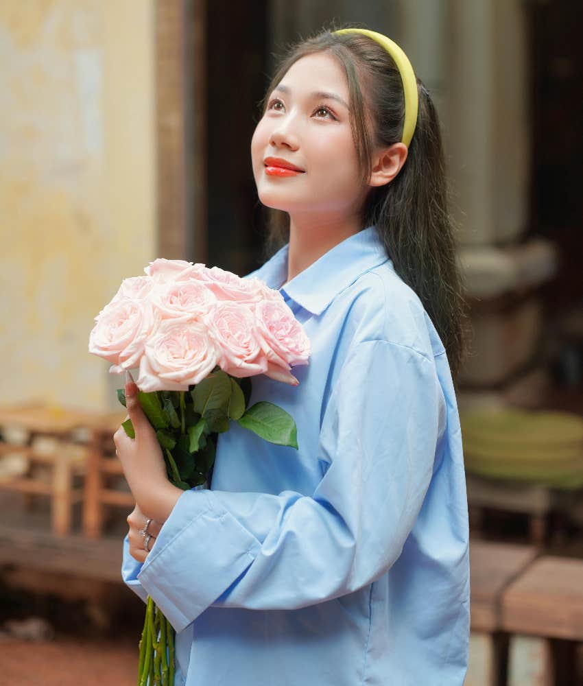 hopeful woman holding flowers looking up