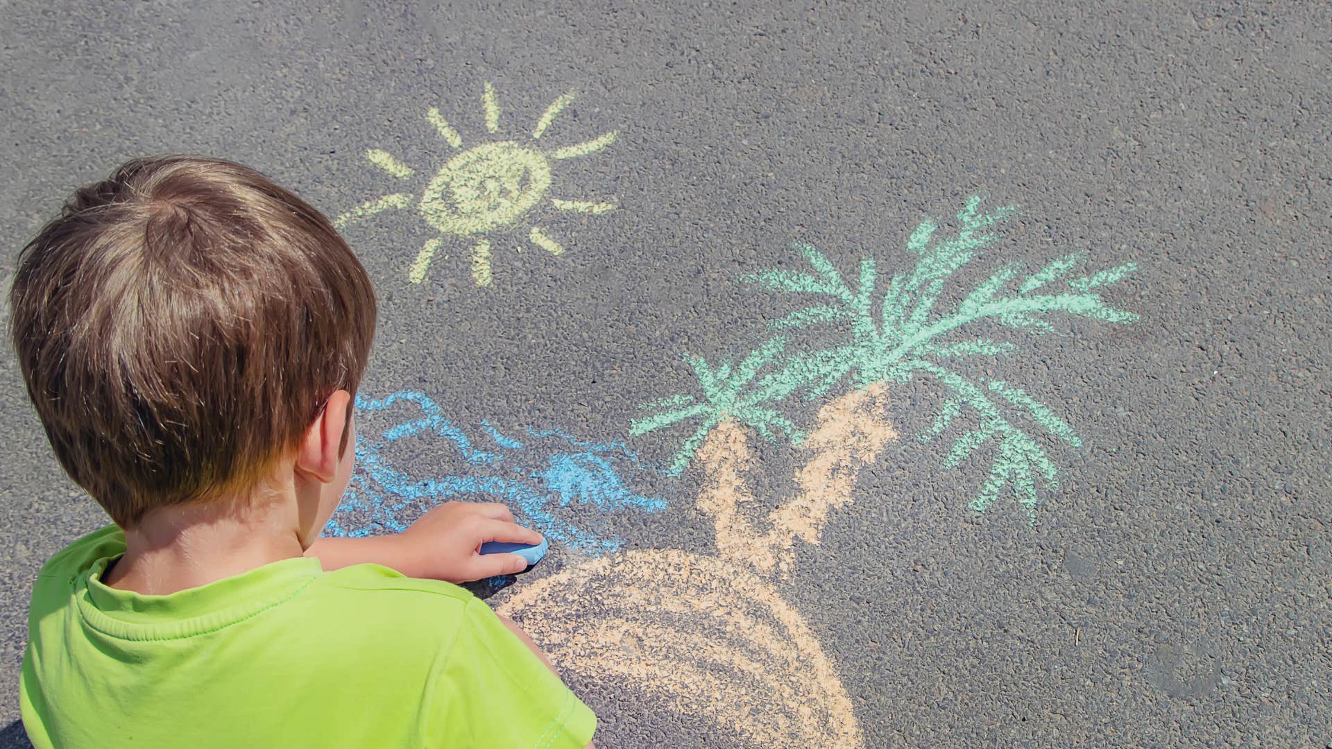 little boy doing chalk art on the sidewalk