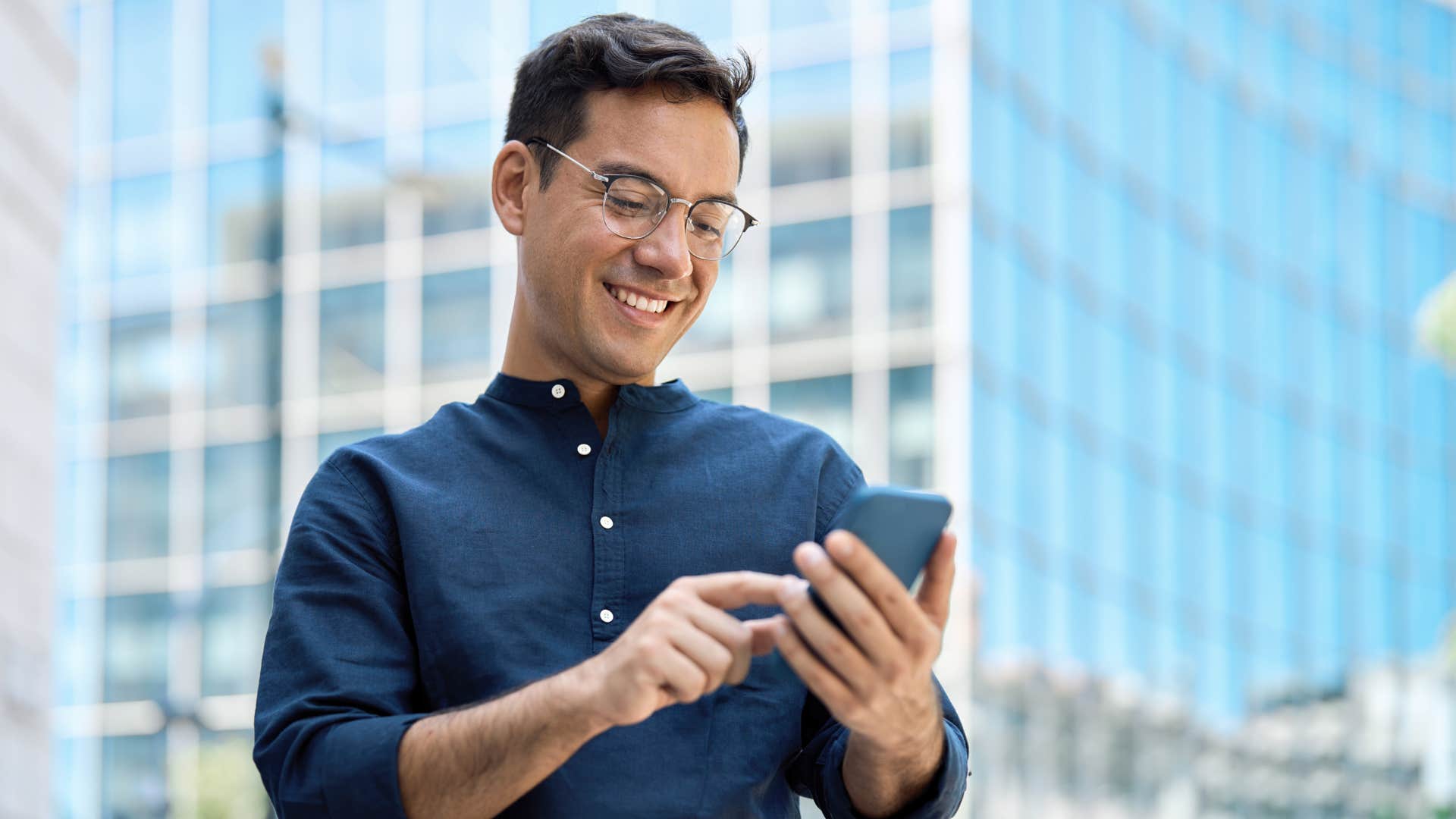man in blue shirt on phone texting as he finds it easier to assert boundaries