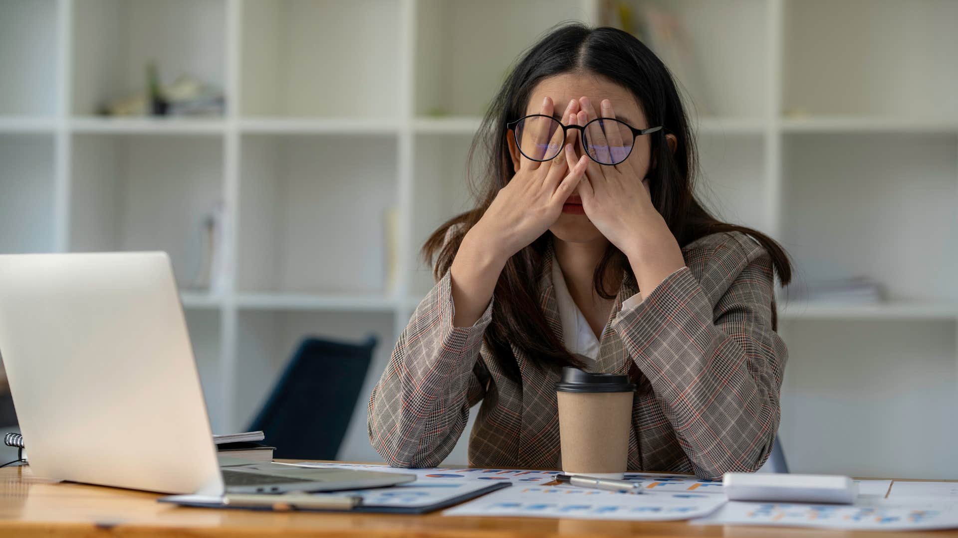woman feeling burned out as she puts head in hand in frustration while sitting at desk