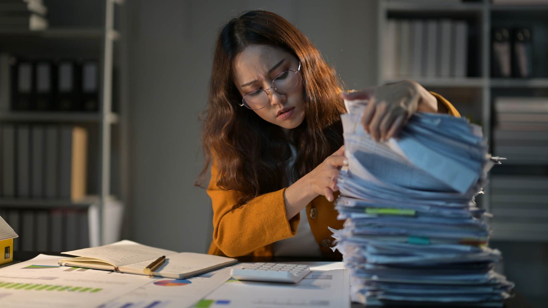 woman in orange preferring to multitask as she looks through stack of papers