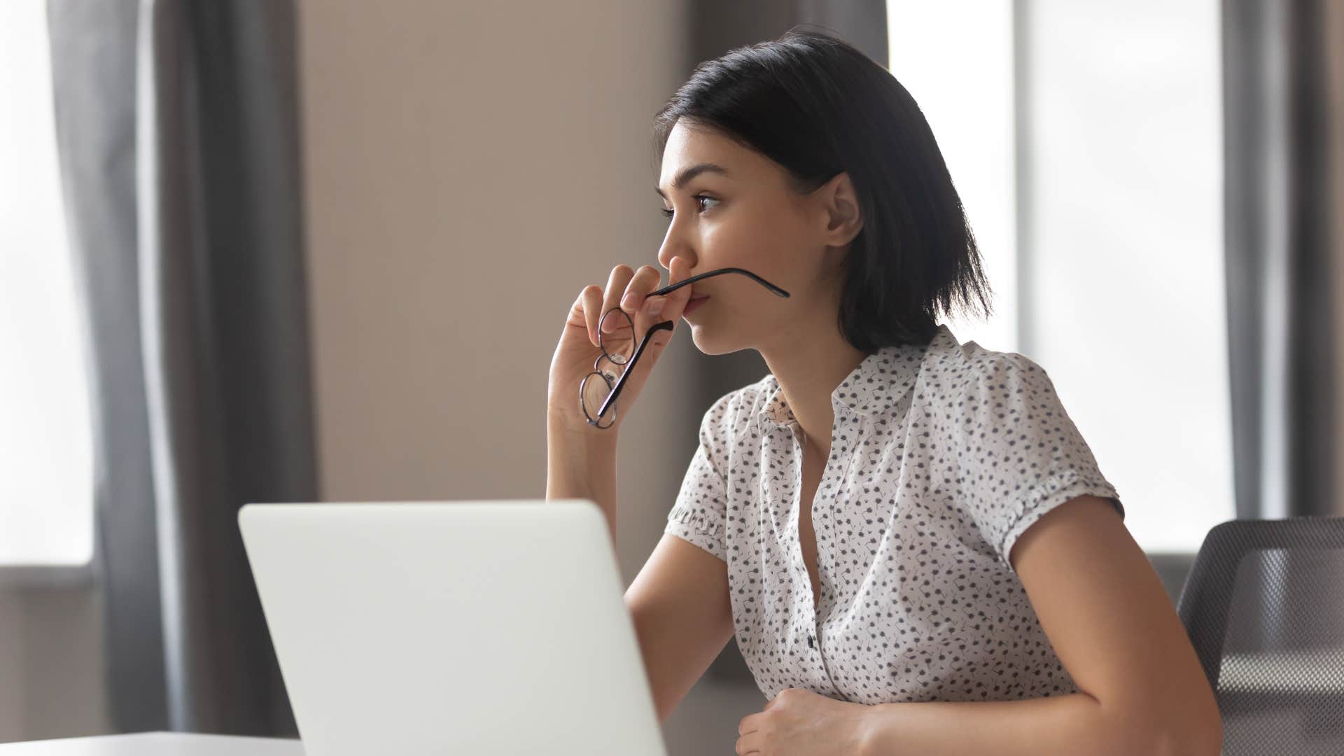 woman in white shirt having social anxiety as she stares off into space with glasses in hand
