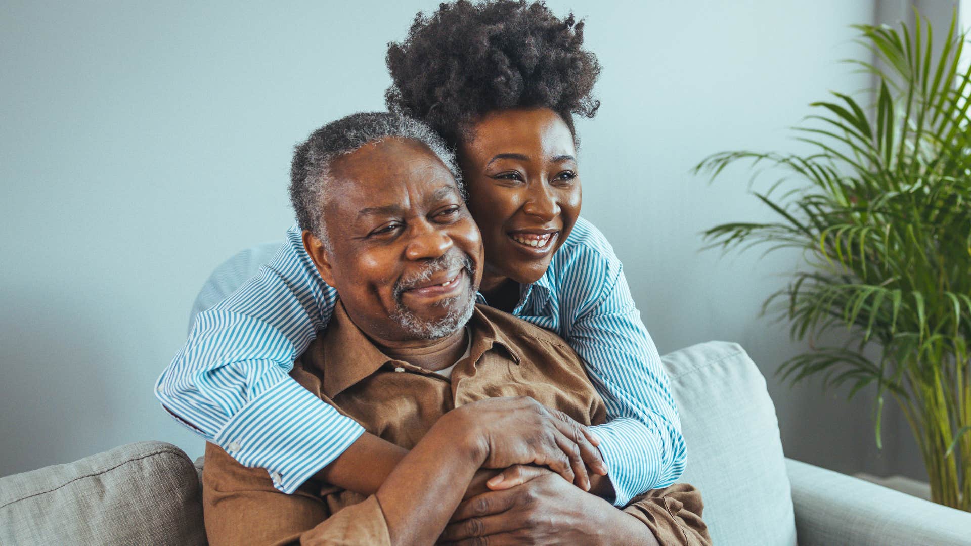 woman hugging her father as one of his caregivers
