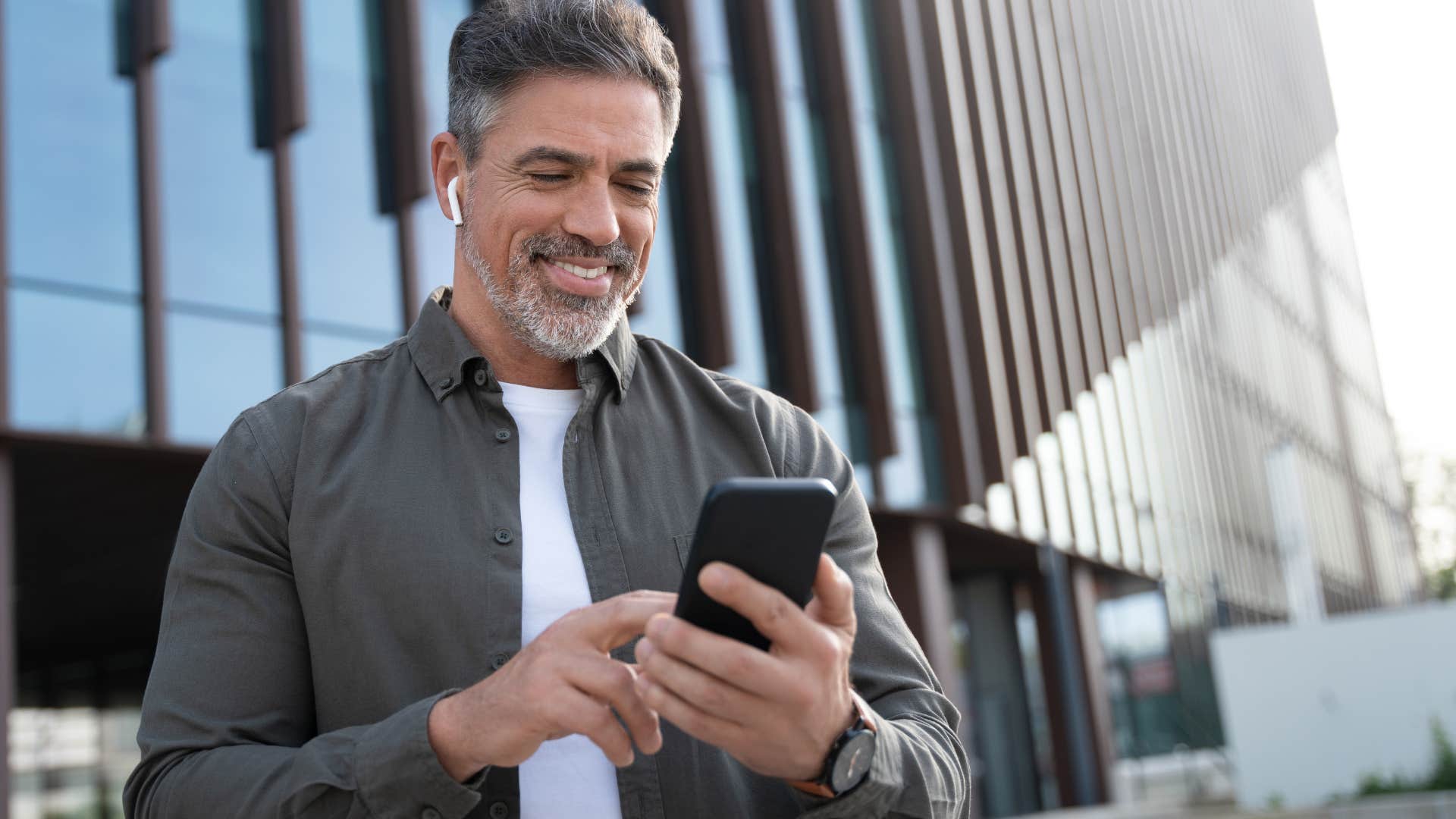 Minimalist man smiling and looking at his phone.