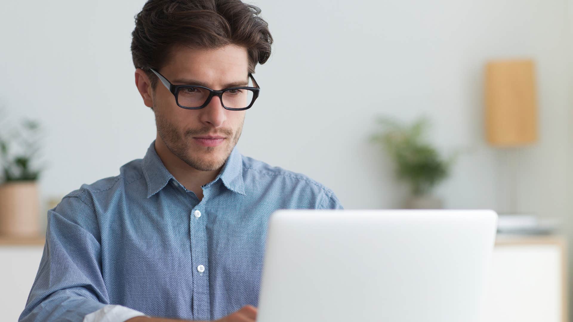Man who struggles with time management working on his laptop.