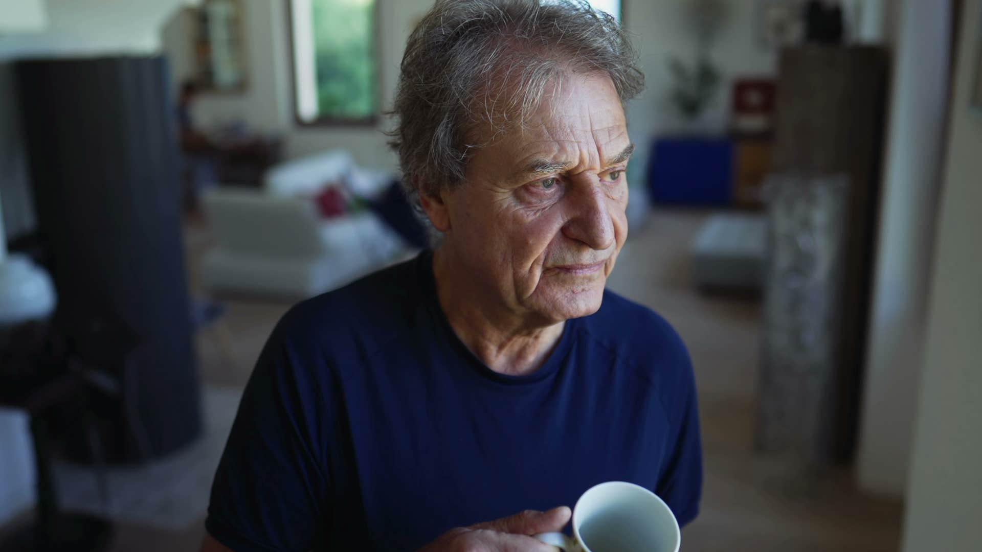 introverted older man drinking coffee at home