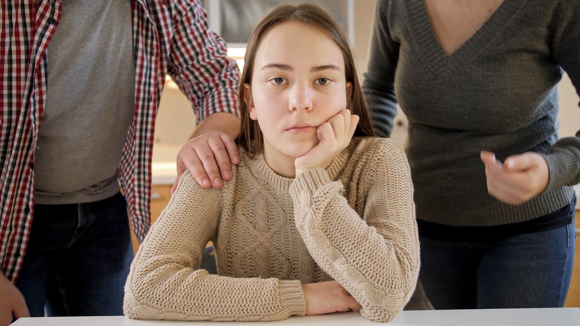 young woman saying it's not a big deal sitting in between her upset parents