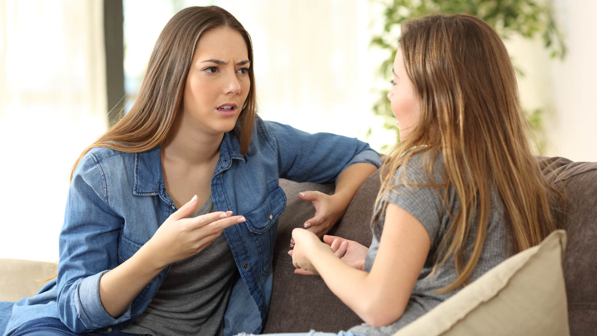 woman in denim asking friend in gray how do you not know that as they sit on couch