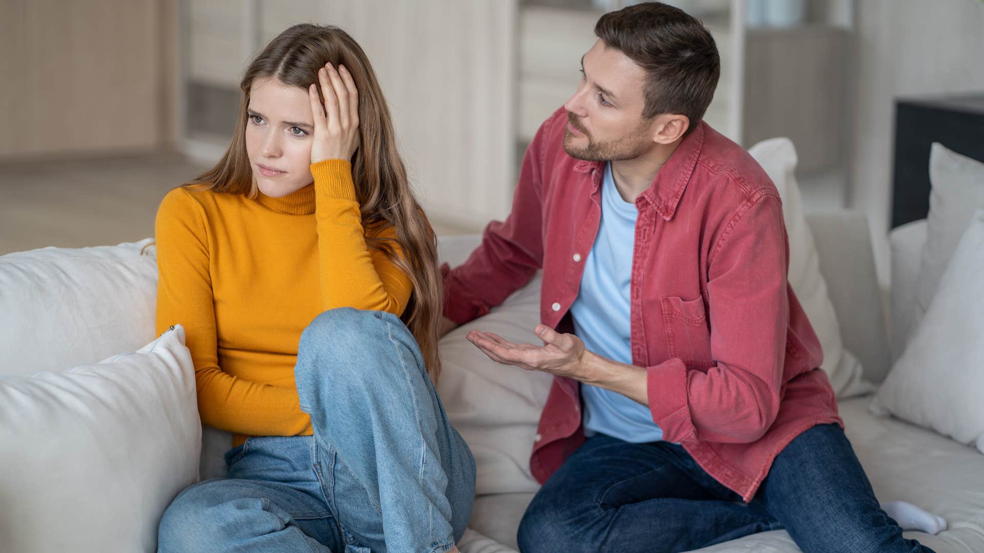man in red jacket pleading with woman to chill out as she turns away from him in orange shirt because she's way too sensitive