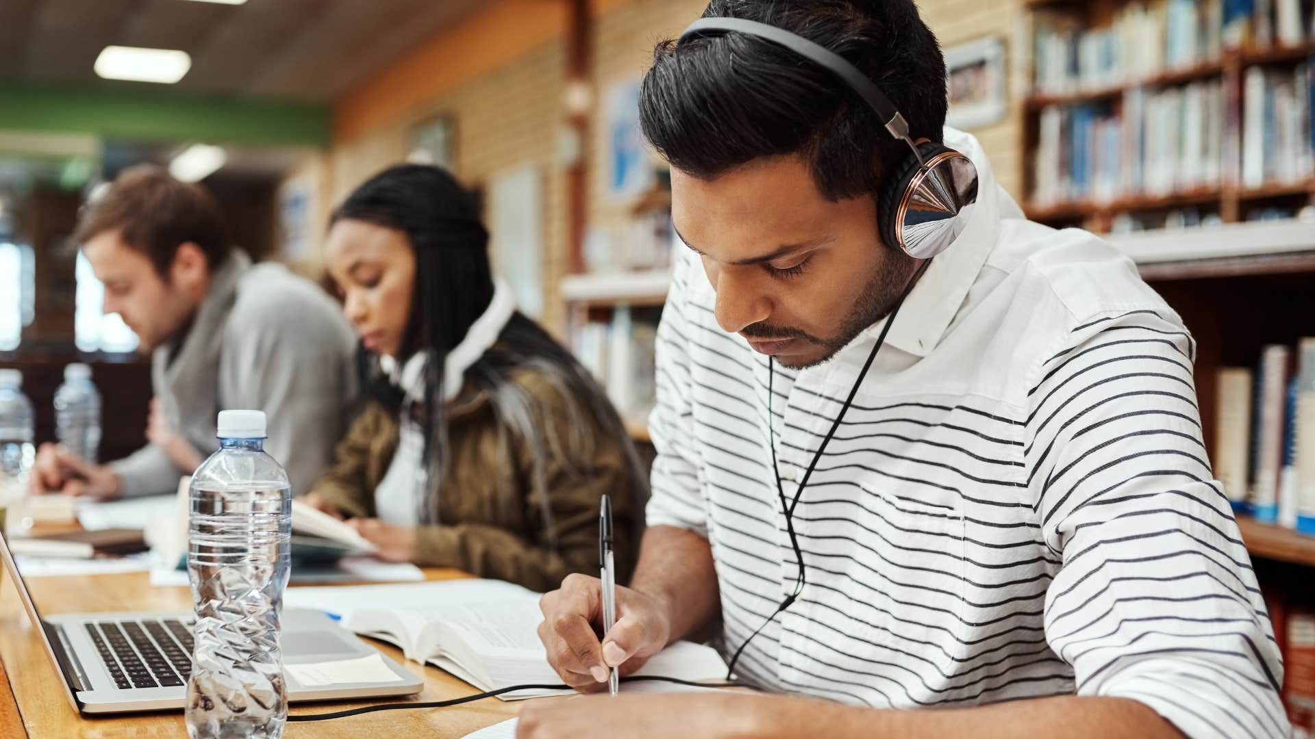 man saying hit the books to himself while studying in the library