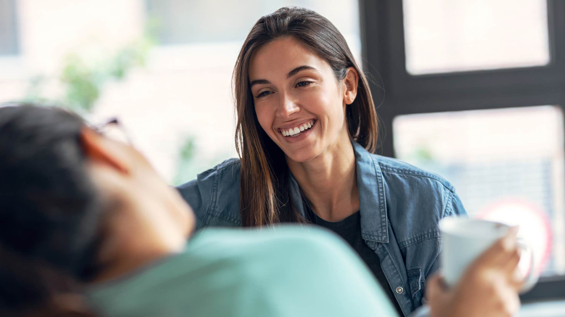 woman laughing and saying knock on wood to her friend for luck