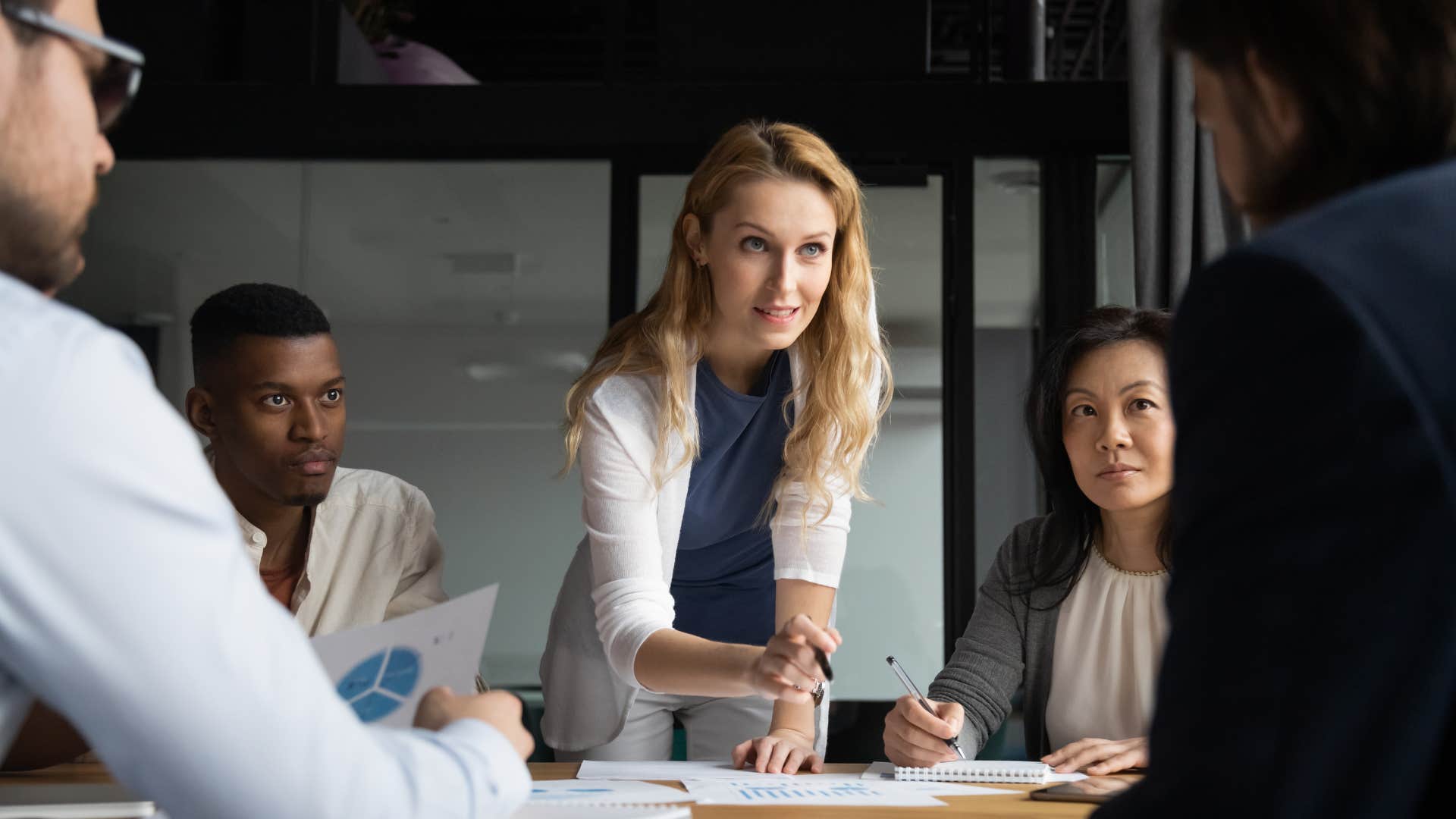 woman in white cardigan saying actually i'm not going to be able to take that on today to people in meeting