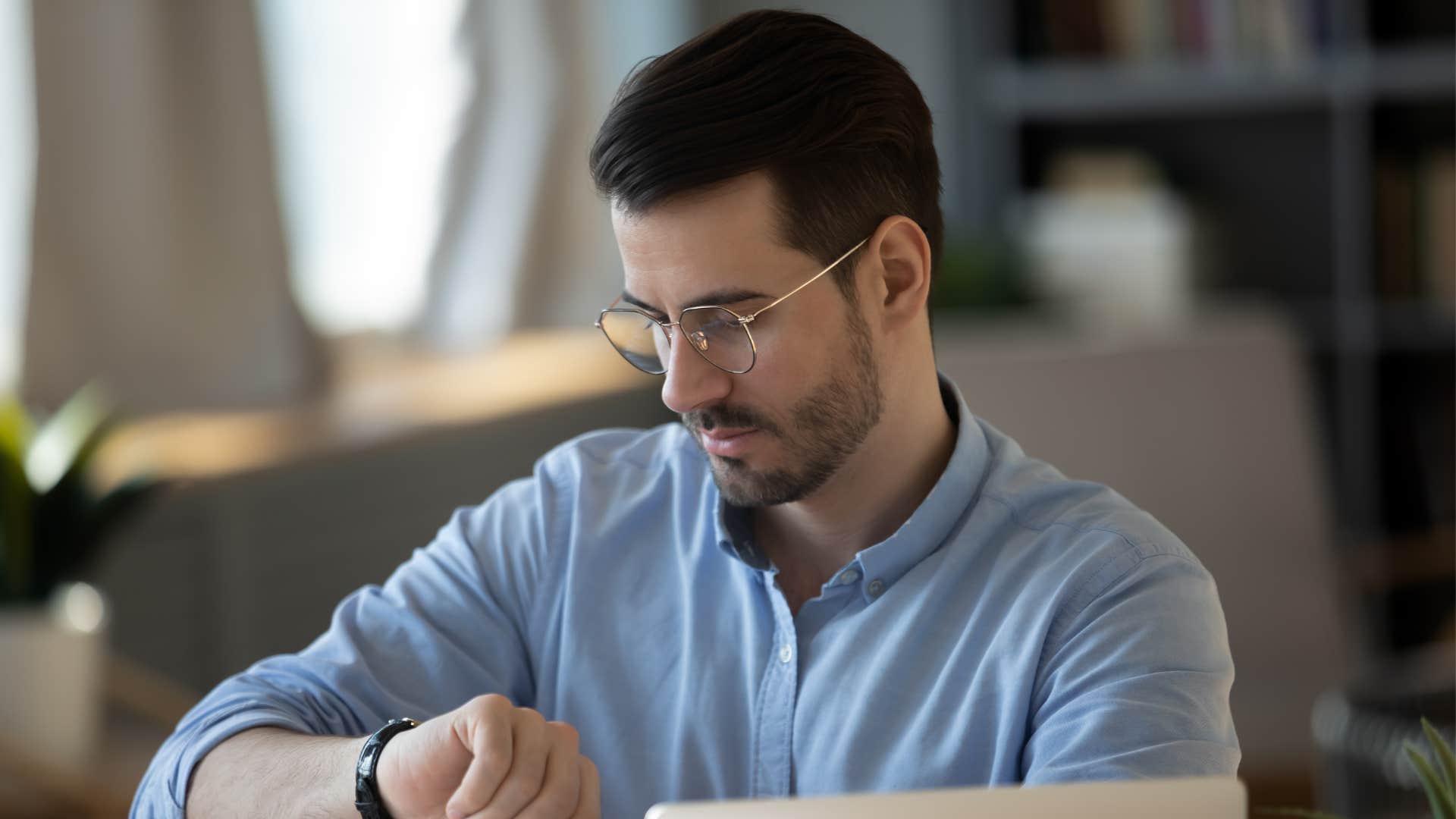 man in blue shirt and glasses checking watch as he says let me check my schedule and get back to you
