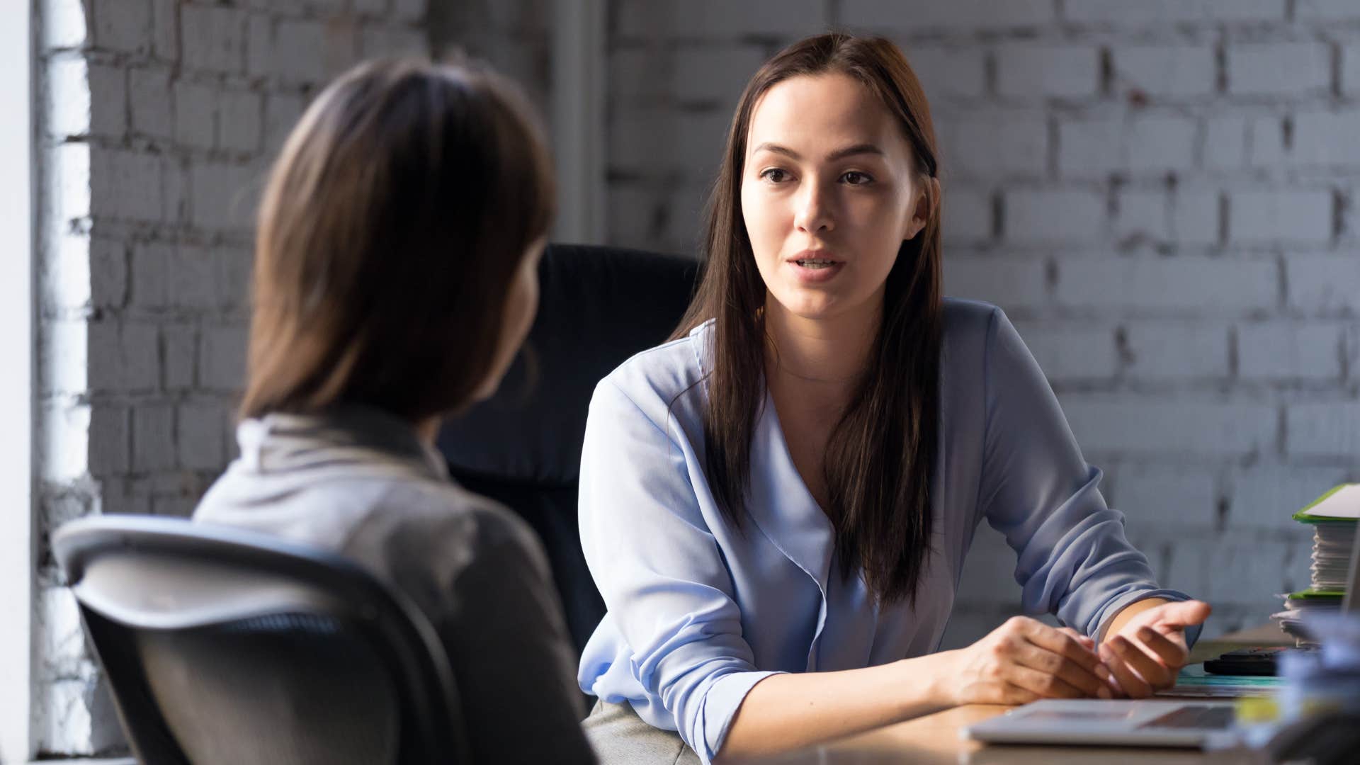 woman in blue shirt telling woman in gray shirt that's outside my scope but i can help you brainstorm ideas