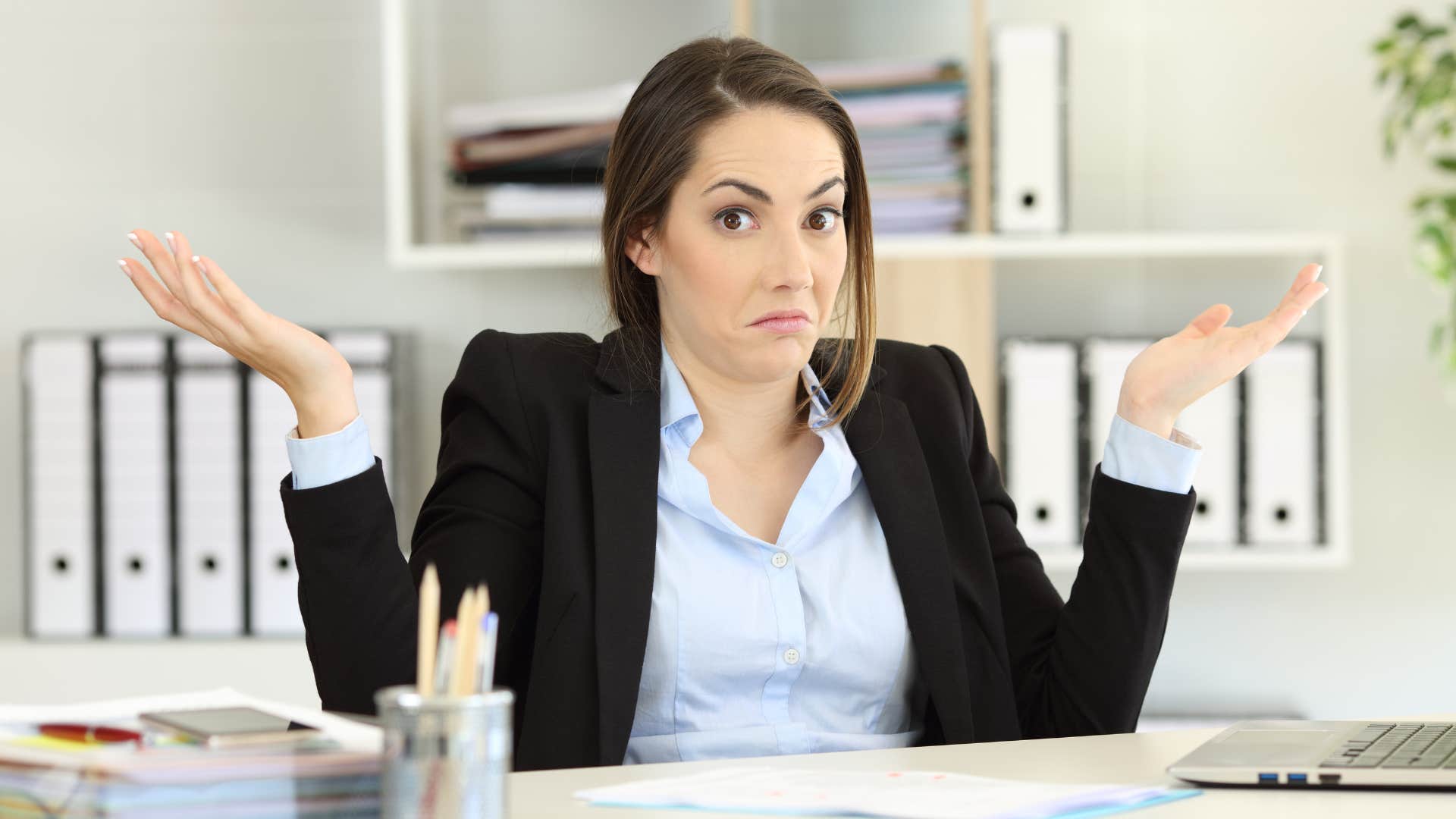 woman shrugging her shoulders in black jacket as she says i'd love to help right now but my hands are full