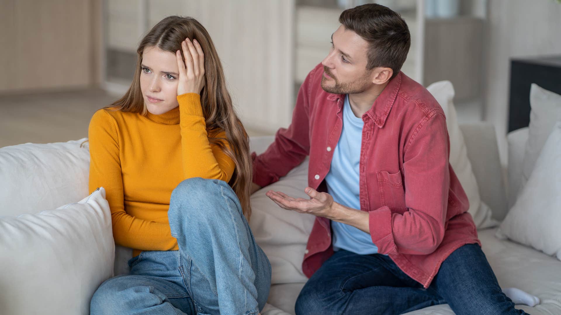 man in red jacket saying sorry i'm not a mind reader as woman in orange sweater turns away from him upset