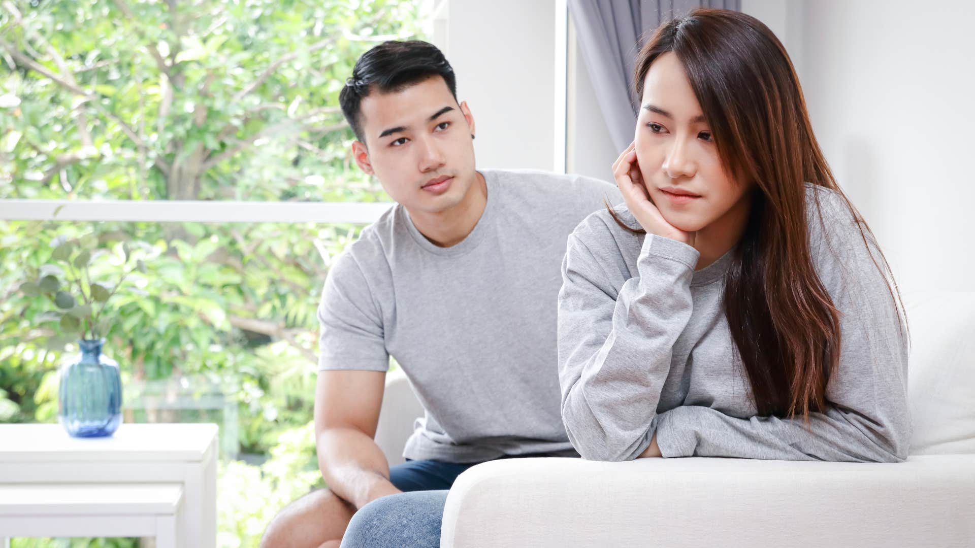 man in gray shirt saying only if you want to though as woman in gray shirt turns away looking annoyed on couch