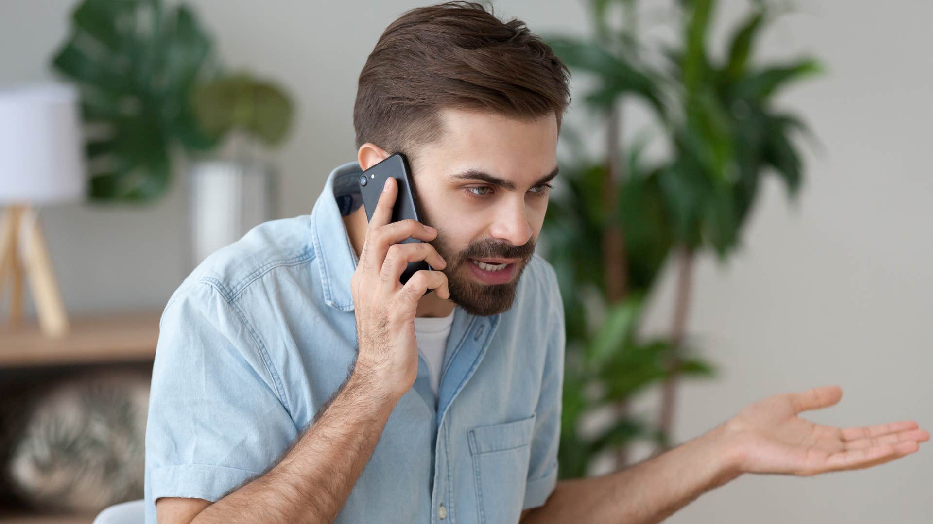man in blue on phone saying sorry i forgot to text you to angry partner as he becomes more angry and frustrated