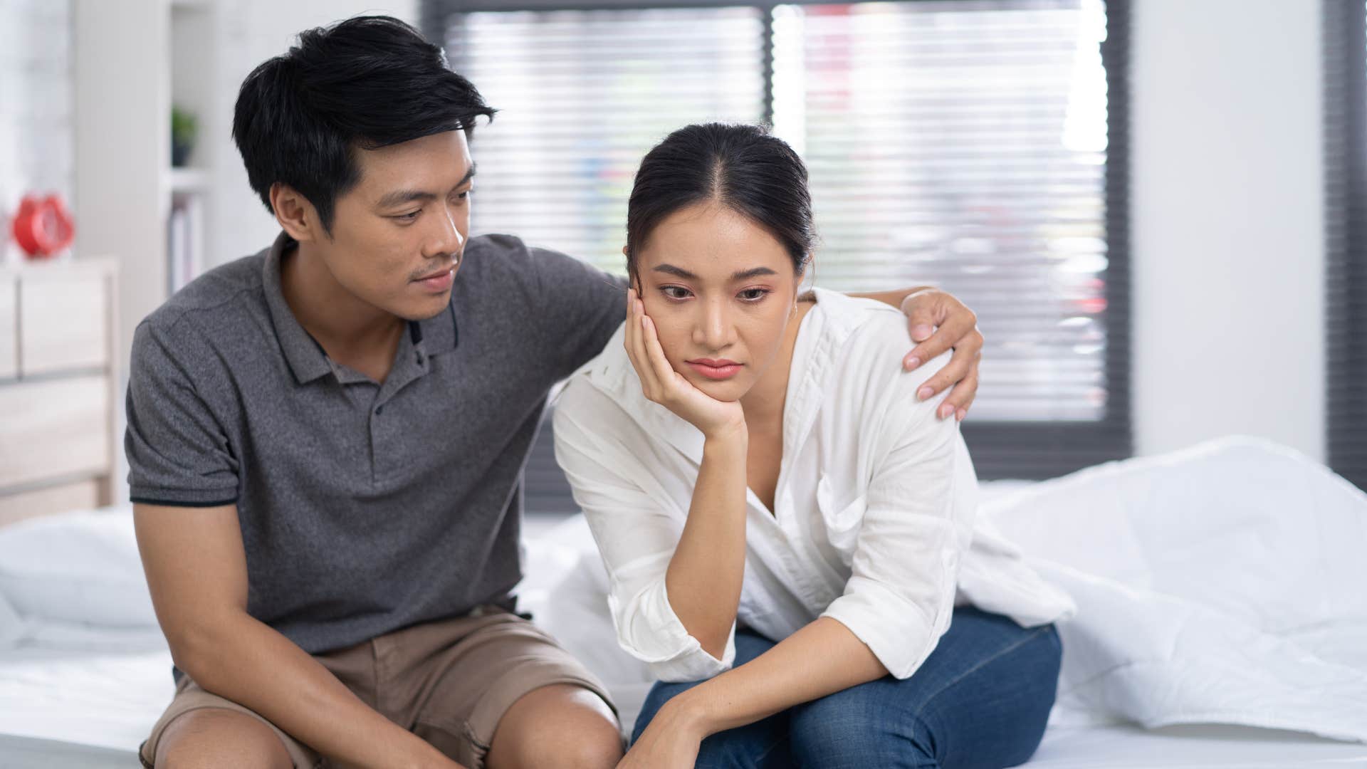 man in dark shirt saying i'm sure you'll figure it out while wrapping his arms around woman in white shirt's shoulders