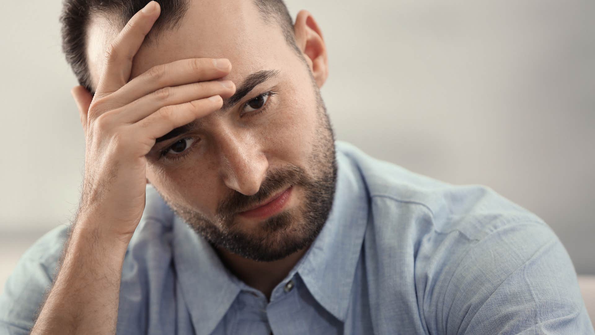 man conflicted about reaching out to his parents looking stressed