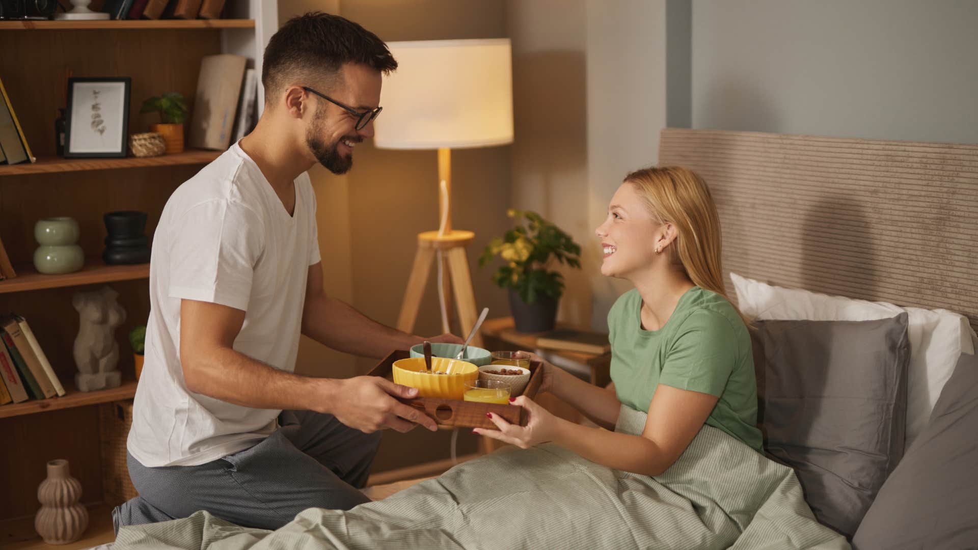 man bringing woman breakfast in bed to show he loves her