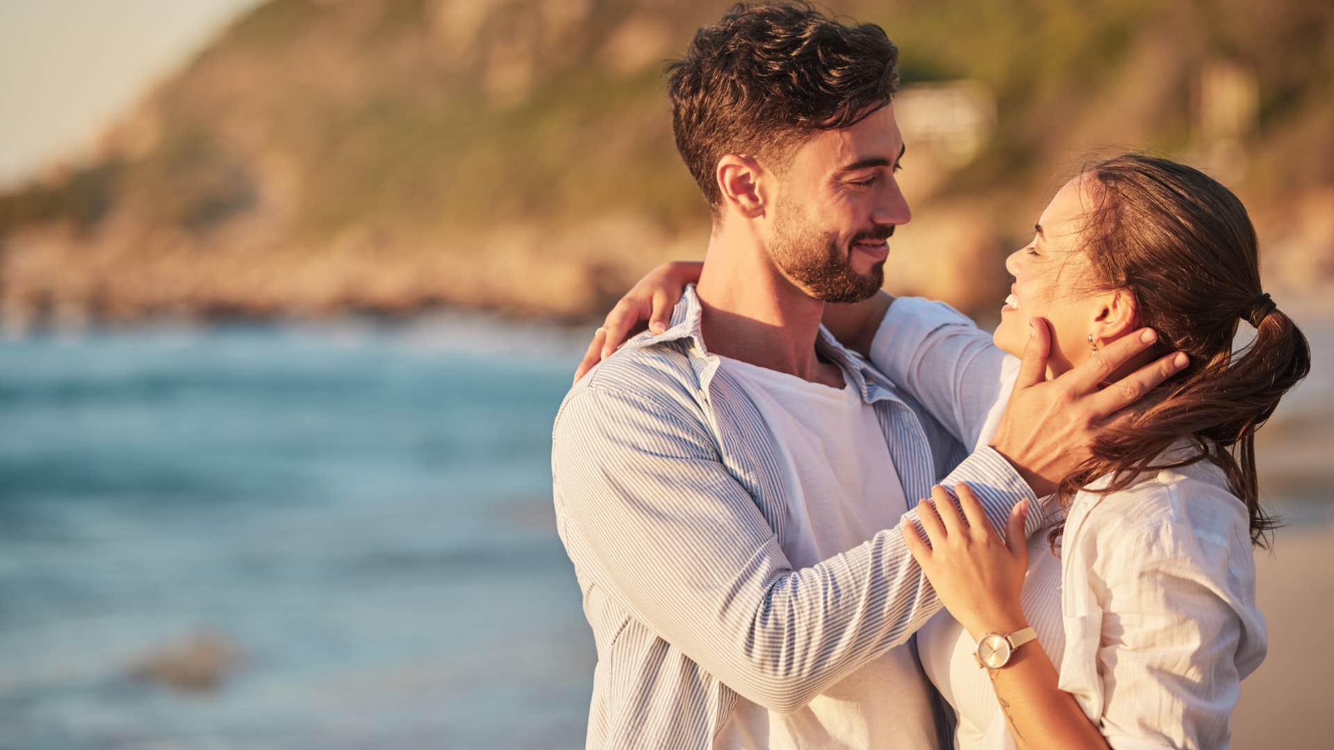 man holding womans face lovingly on the beach